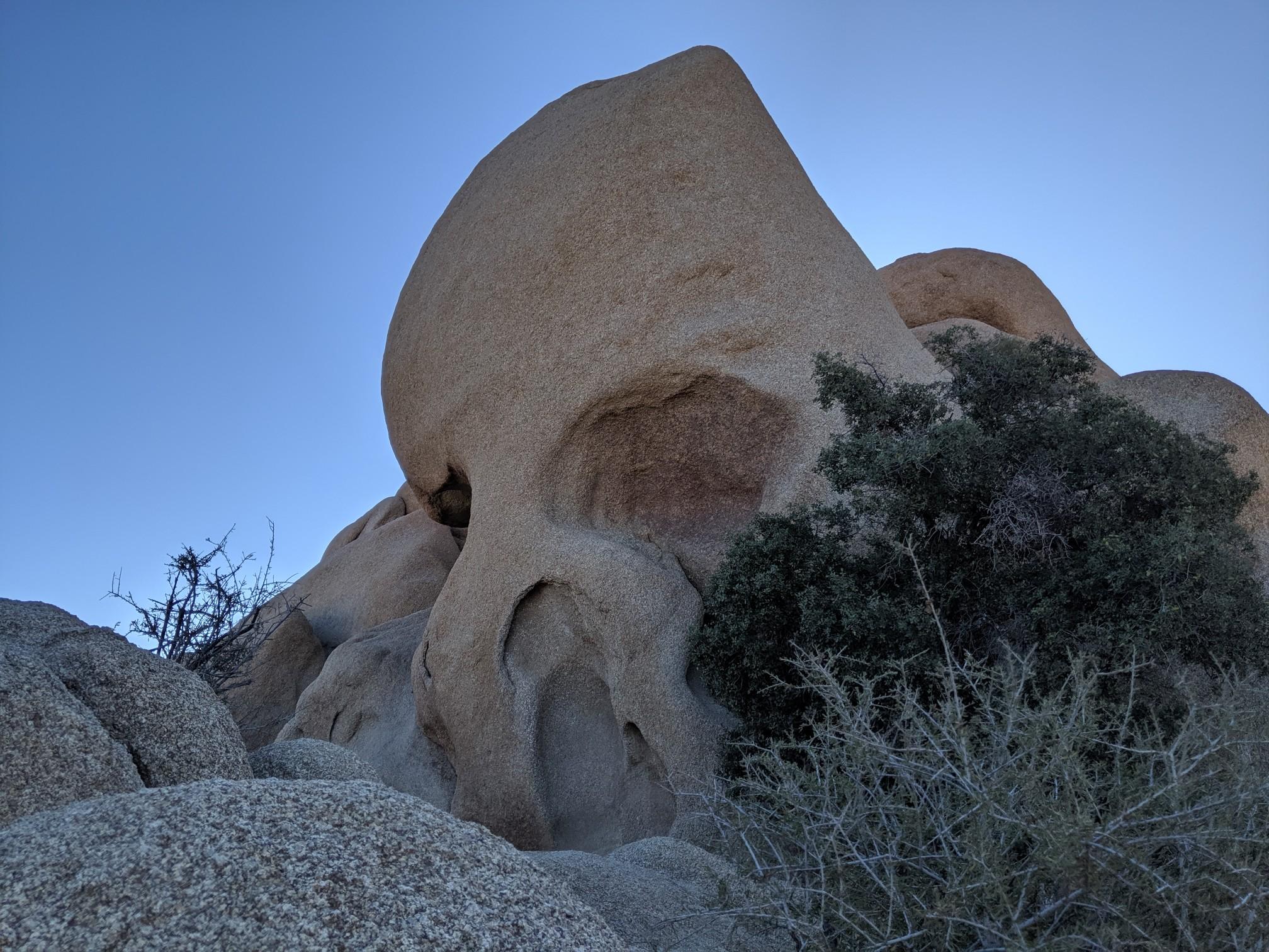 Close-up of a large rock formation resembling a skull under a clear sky.