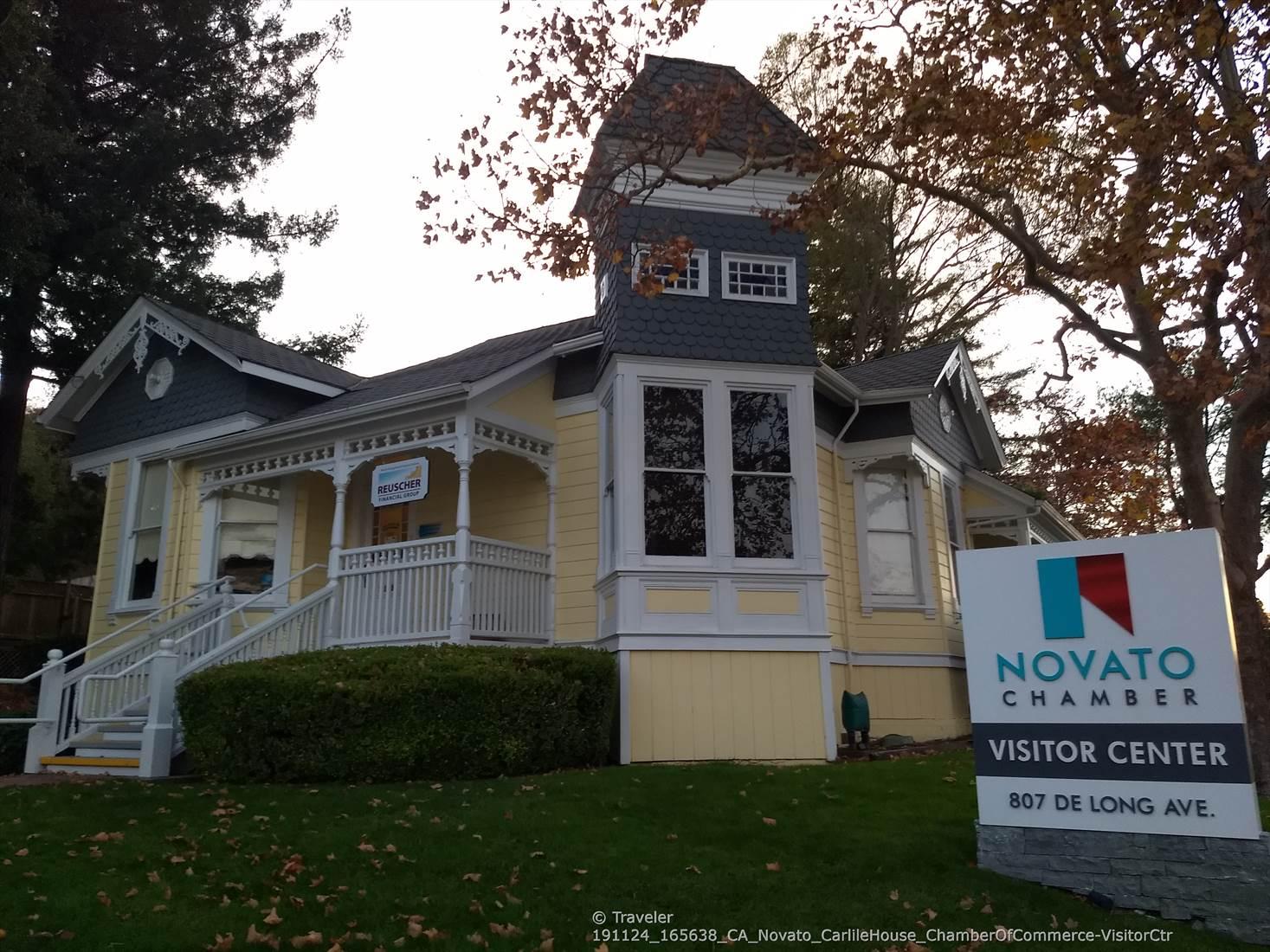Yellow Victorian-style house with a tower, surrounded by green lawn and trees.