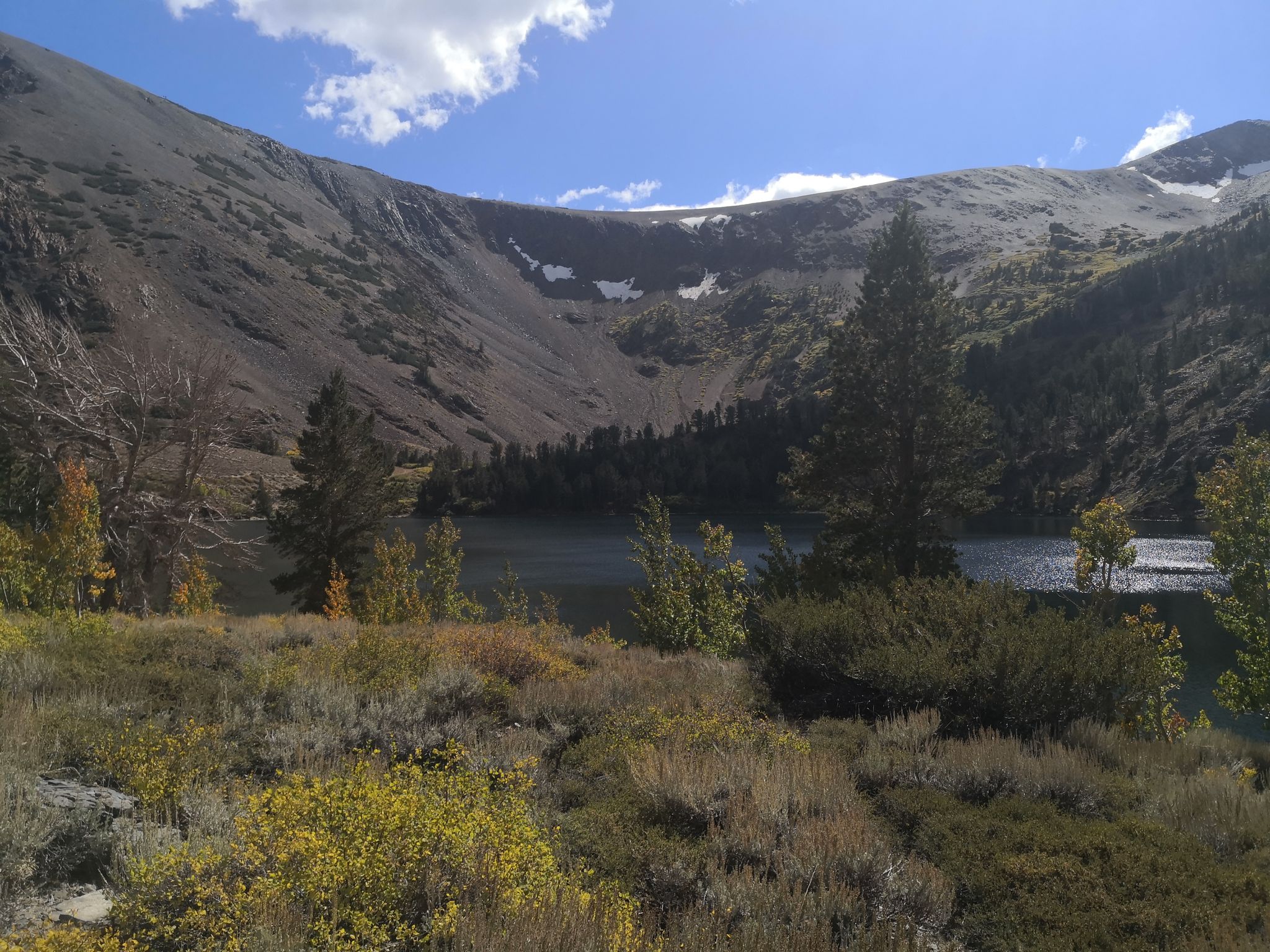 Bright day over a mountain lake with rocky slopes and scattered trees. - Big Virginia Lake loop from Conway Summit