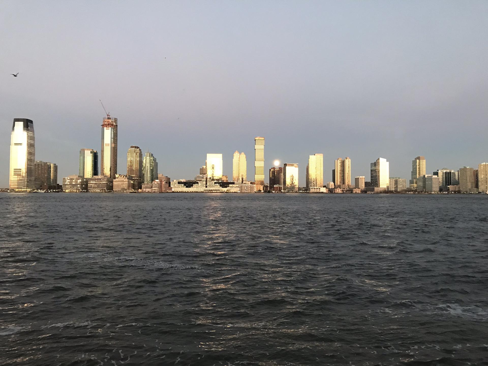 City skyline across water, illuminated by golden hour sunlight.