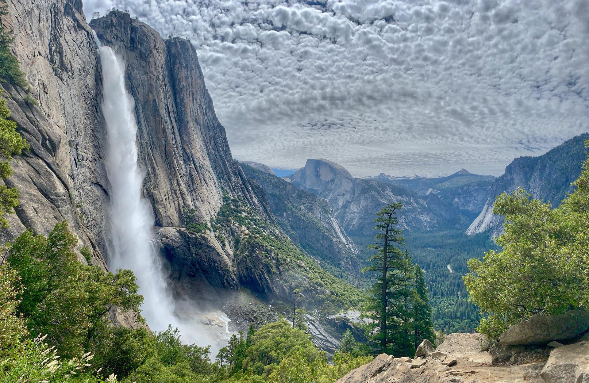 A powerful waterfall plunges down a sheer cliff into a green valley.
