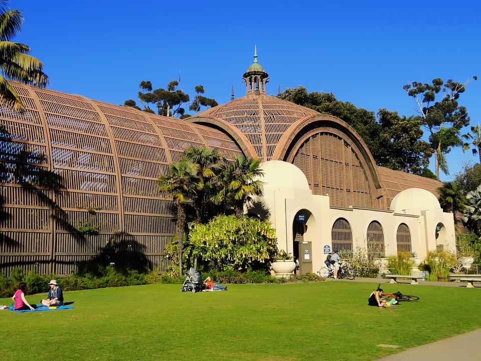 Ornate building with domed roof, arches, and people relaxing on a sunny lawn.