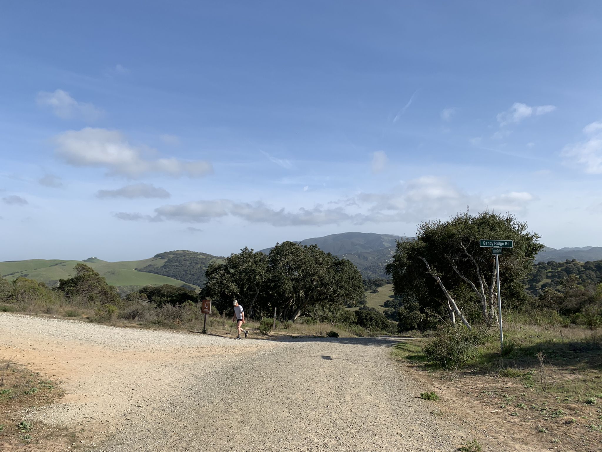 Person walking on a dirt road through hilly, green landscape under blue sky. - Trail 41 and Trail 36 Loop