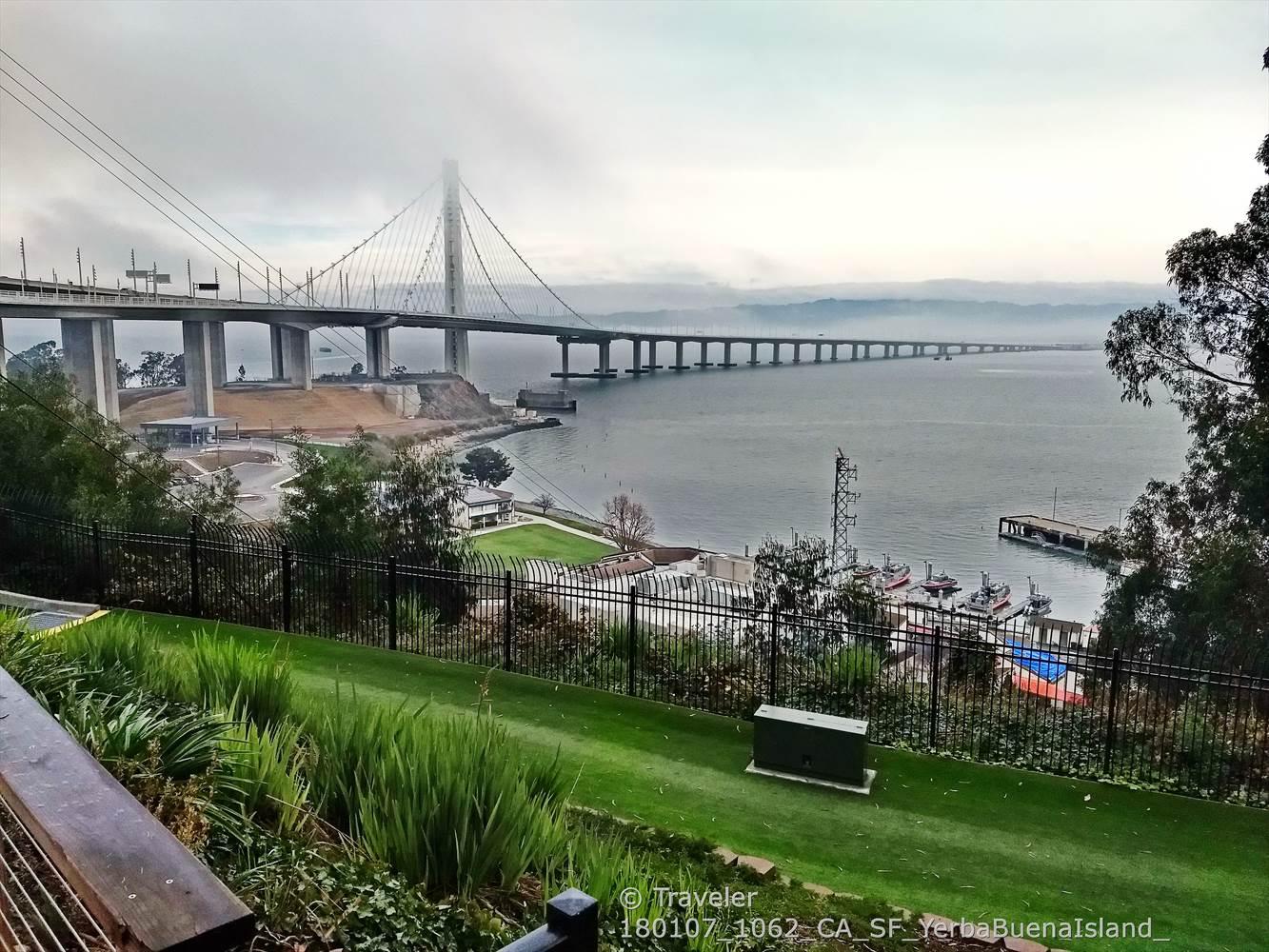 Long suspension bridge extending into a misty horizon over calm water.