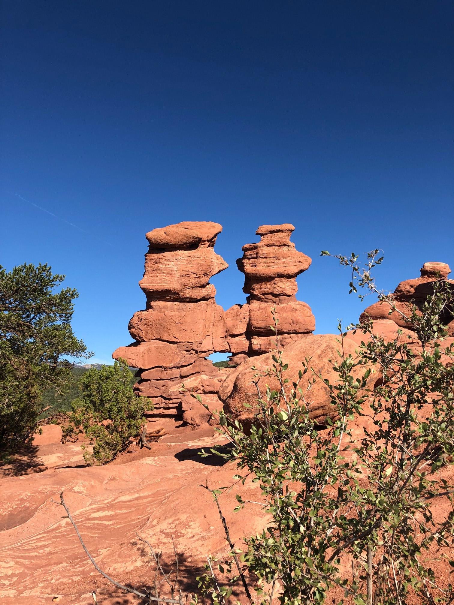 Unique stacked red rock formations stand against a clear blue sky.
