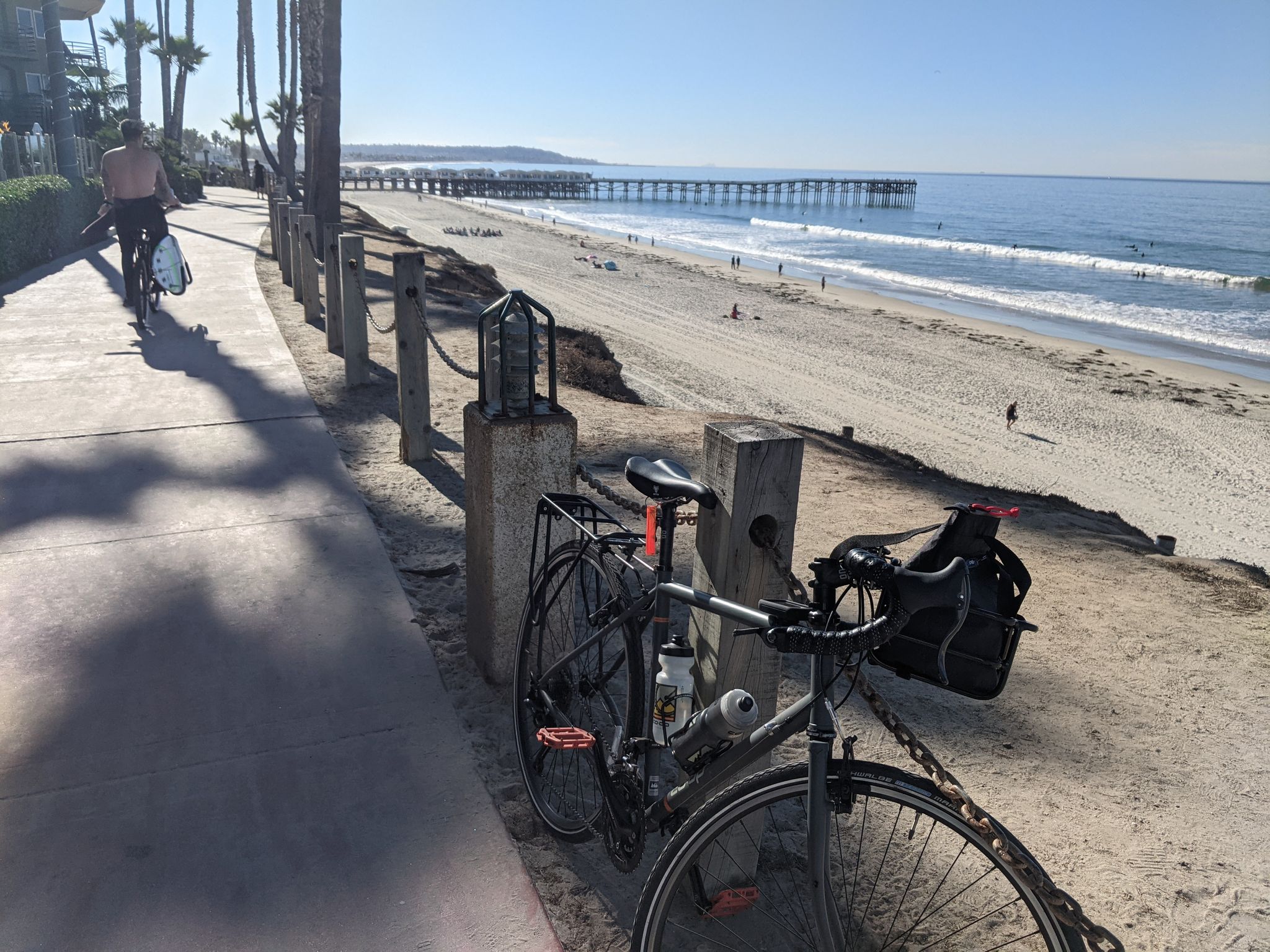 Bicycle parked on a sunny path overlooking a beach and distant pier. - View of La Jolla Hermosa Park – La Jolla Strand Park Beach loop from Pacific Beach