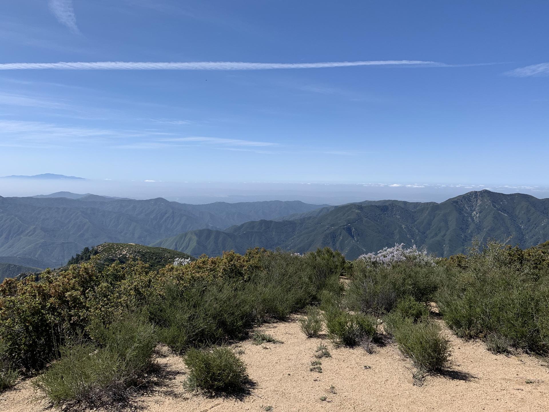A wide mountain vista under a clear blue sky with distant peaks.