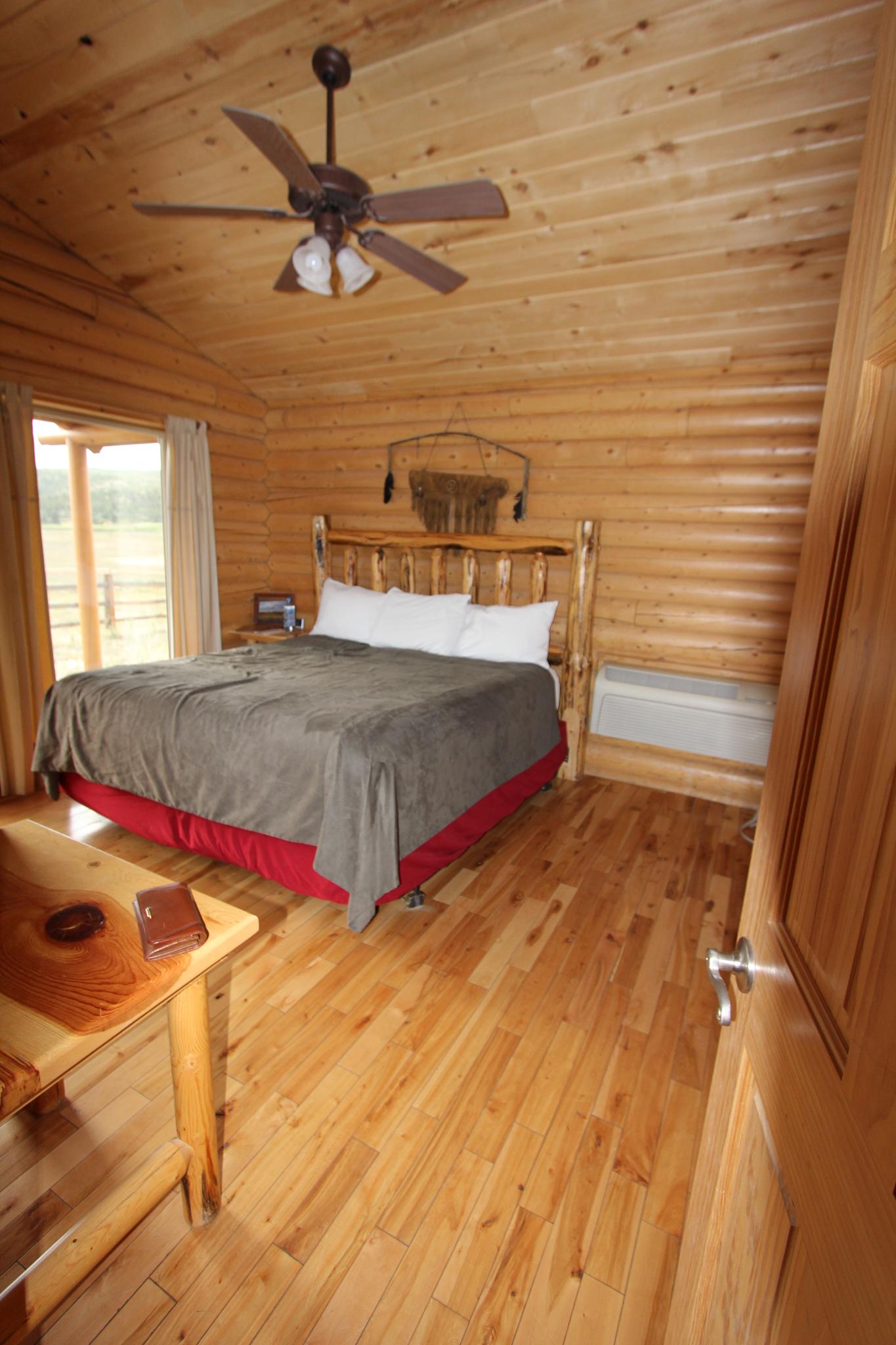 A rustic log cabin bedroom with a large bed and wooden interior.