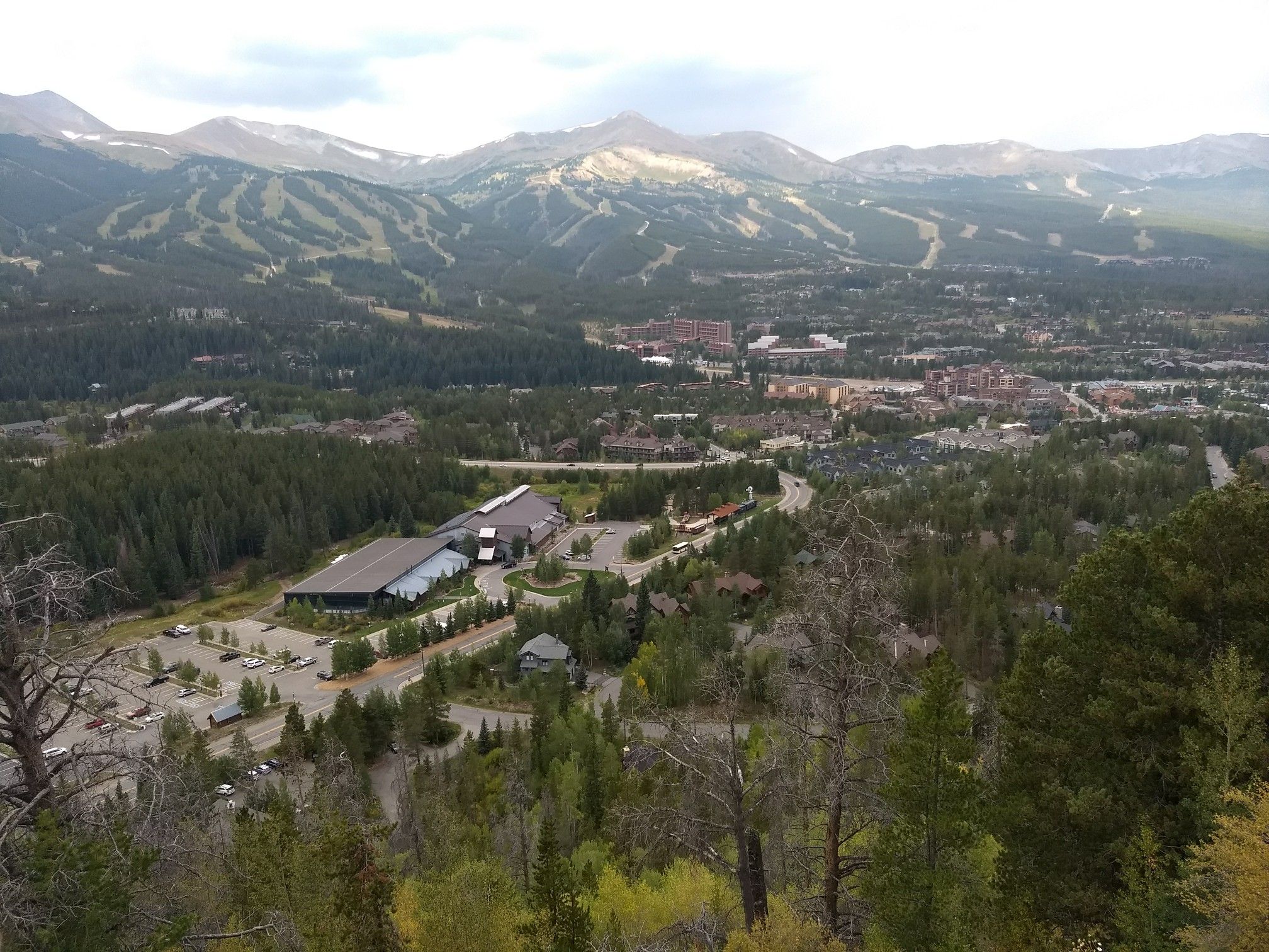 Wide aerial view of a town nestled in a valley with mountains and ski slopes. - Breckenridge Overlook loop