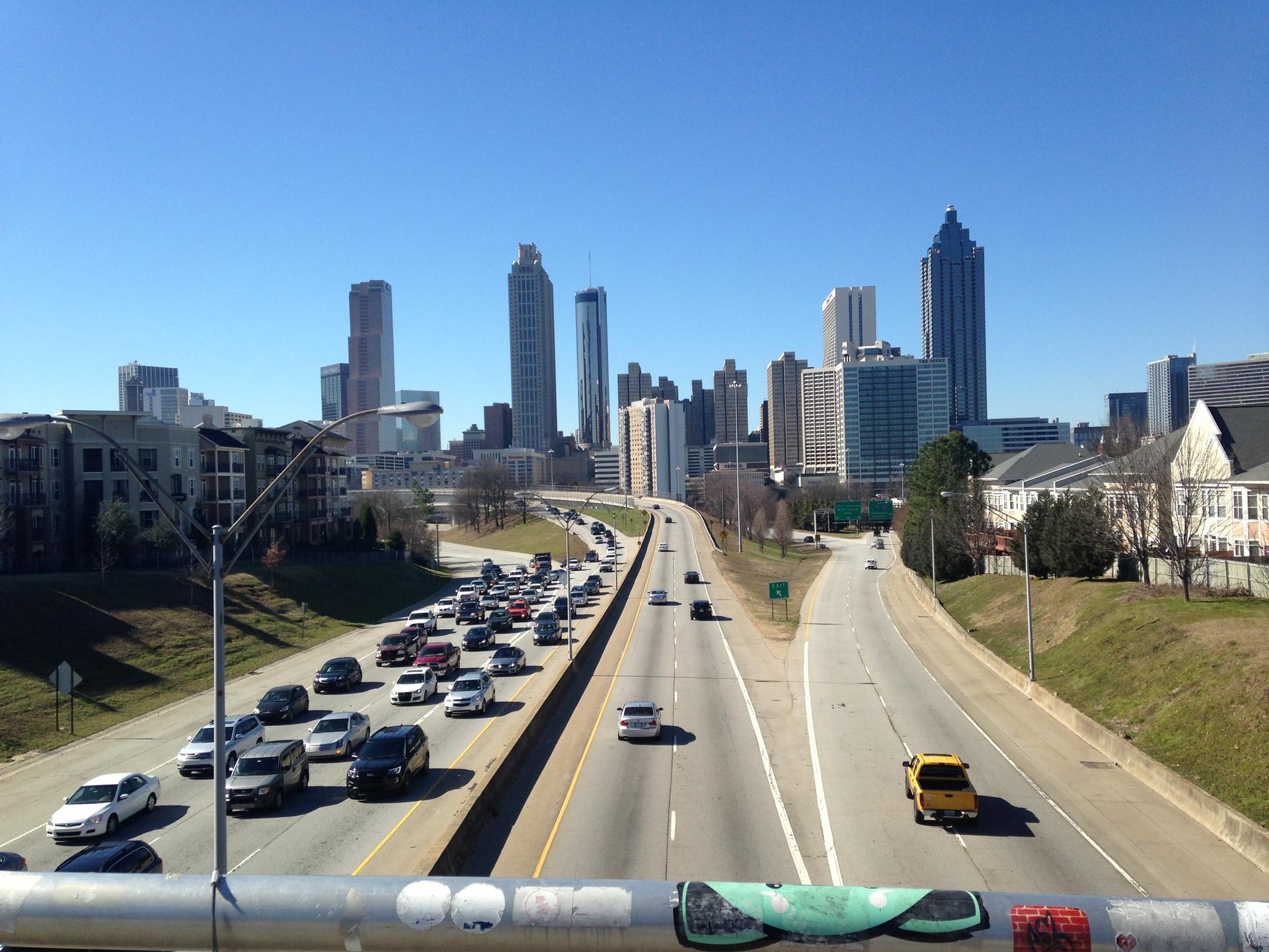 Busy highway traffic leading to a city skyline on a clear sunny day.