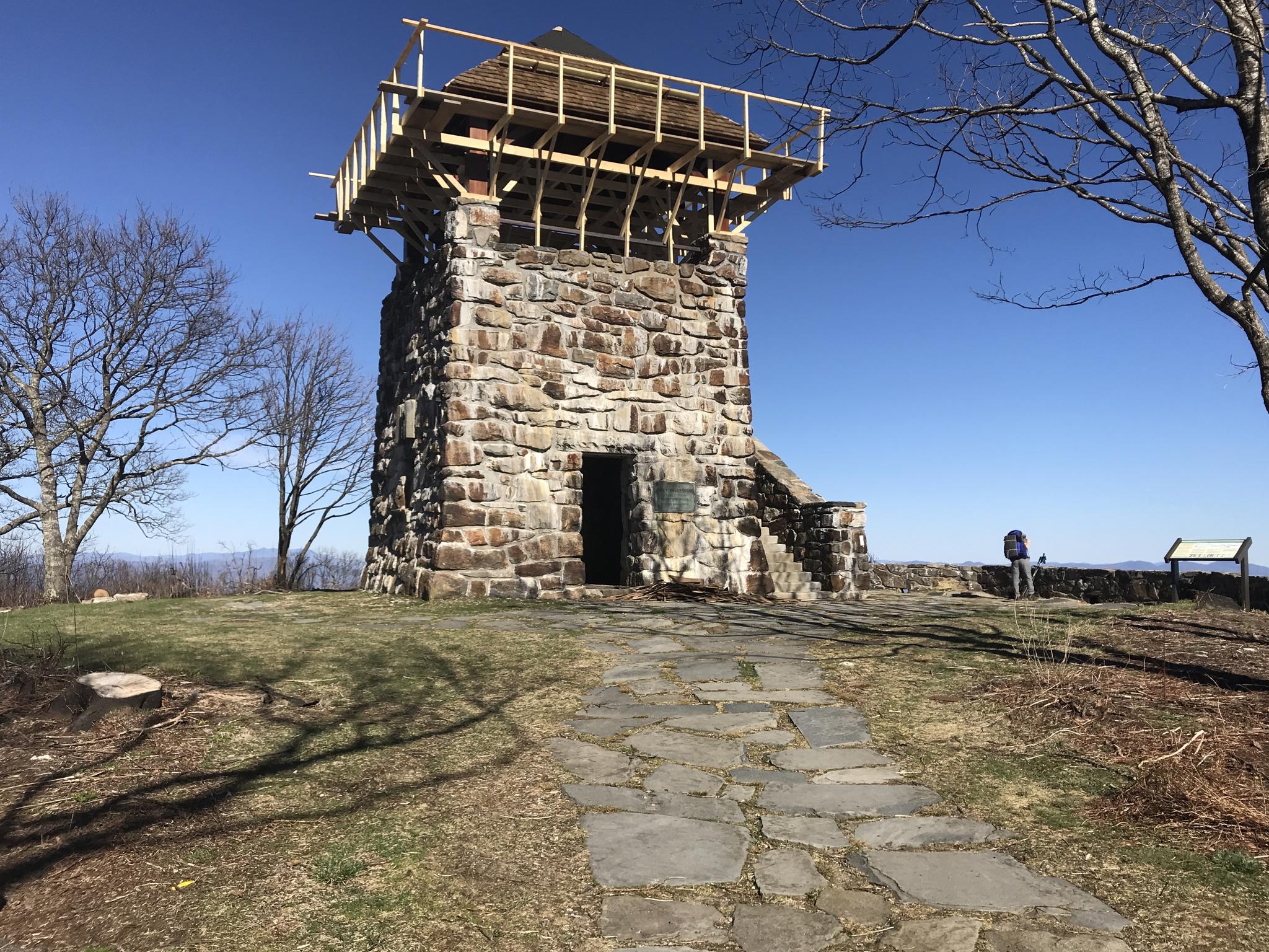 Stone tower with scaffolding on a sunny day, stone path leading to it.