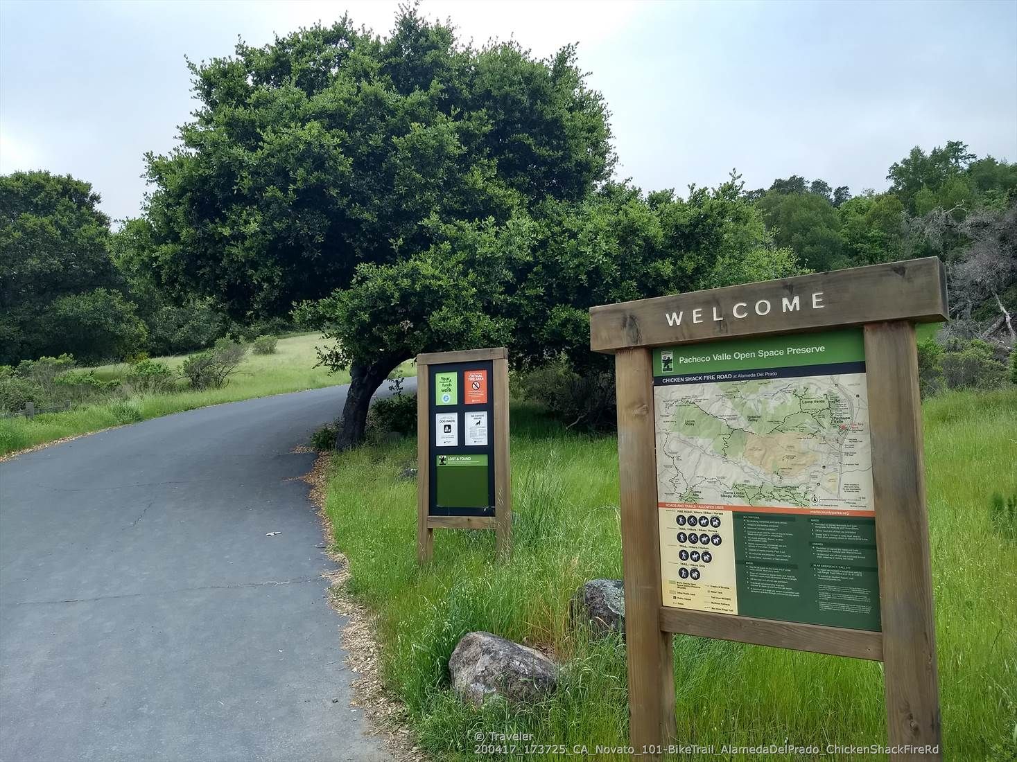 Two information signs beside a paved road with green trees under a cloudy sky. - Ponti Trail and Chicken Shack Fire Road Loop