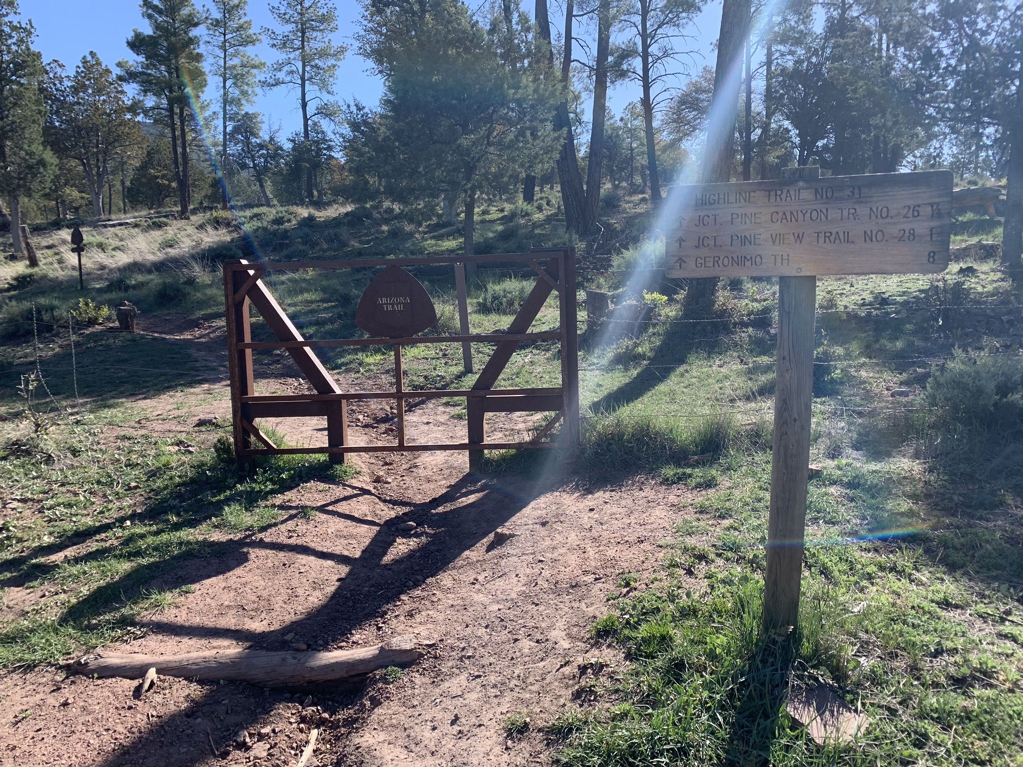 Sunny trail entrance with a wooden gate and signpost, lens flare. - Arizona Trail: Passage 26 - Highline