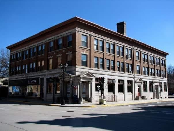 Large brick building on a sunny street corner with clear blue sky.