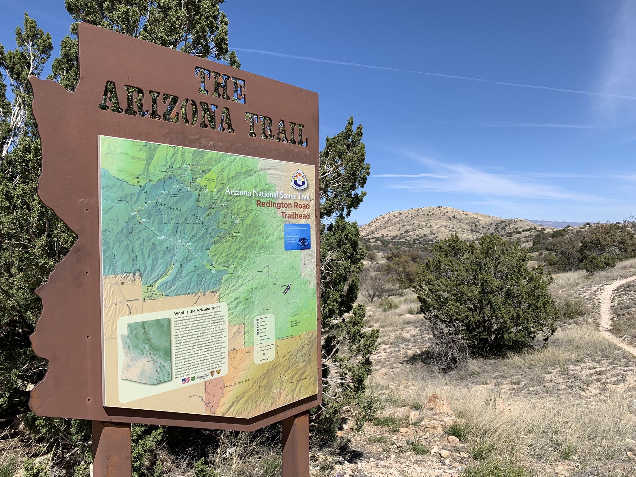 Information sign with map in a sunny desert landscape with green trees. - Redington Road FS371