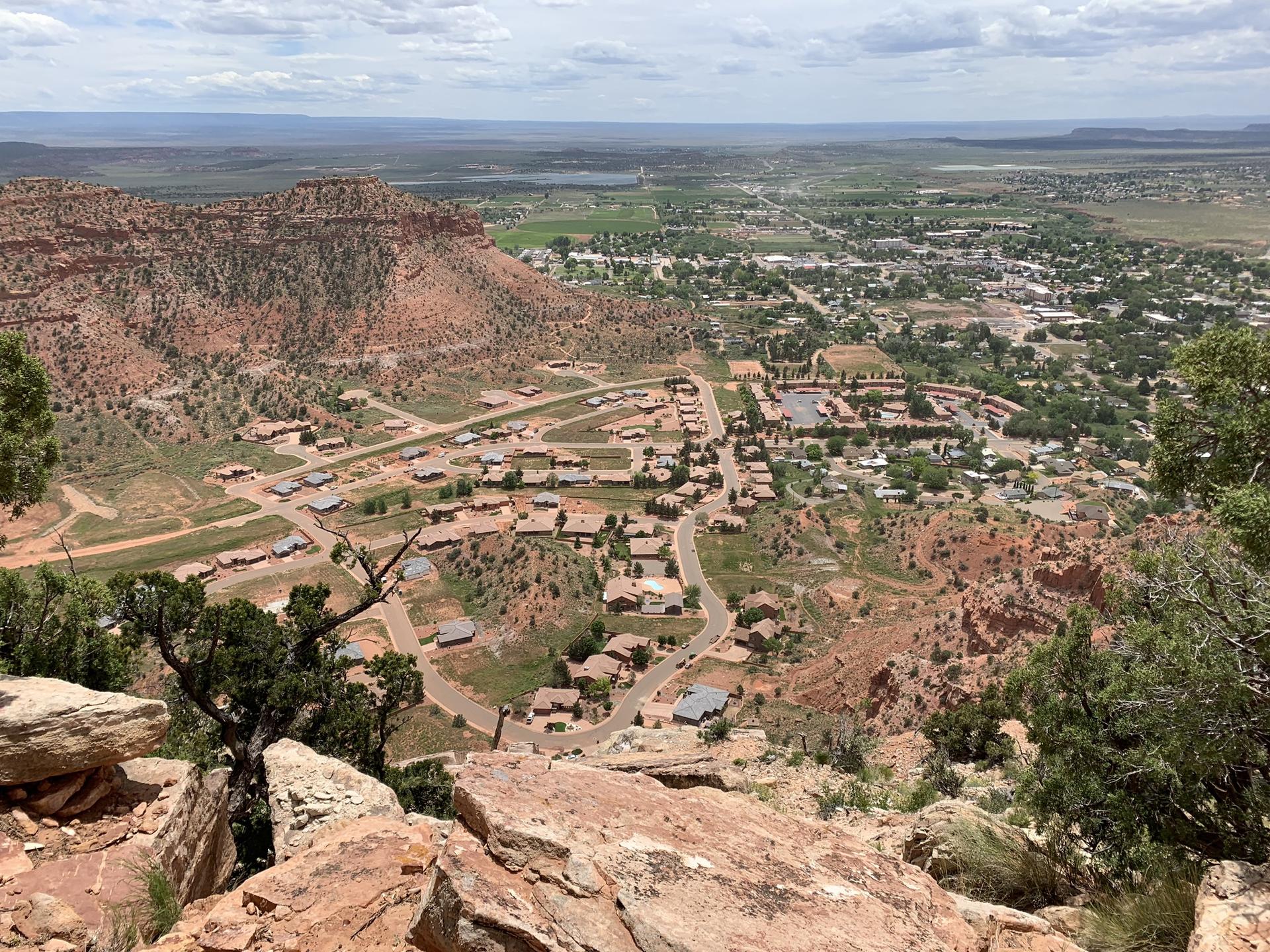 Expansive view of a town nestled in a valley, surrounded by red rocks.