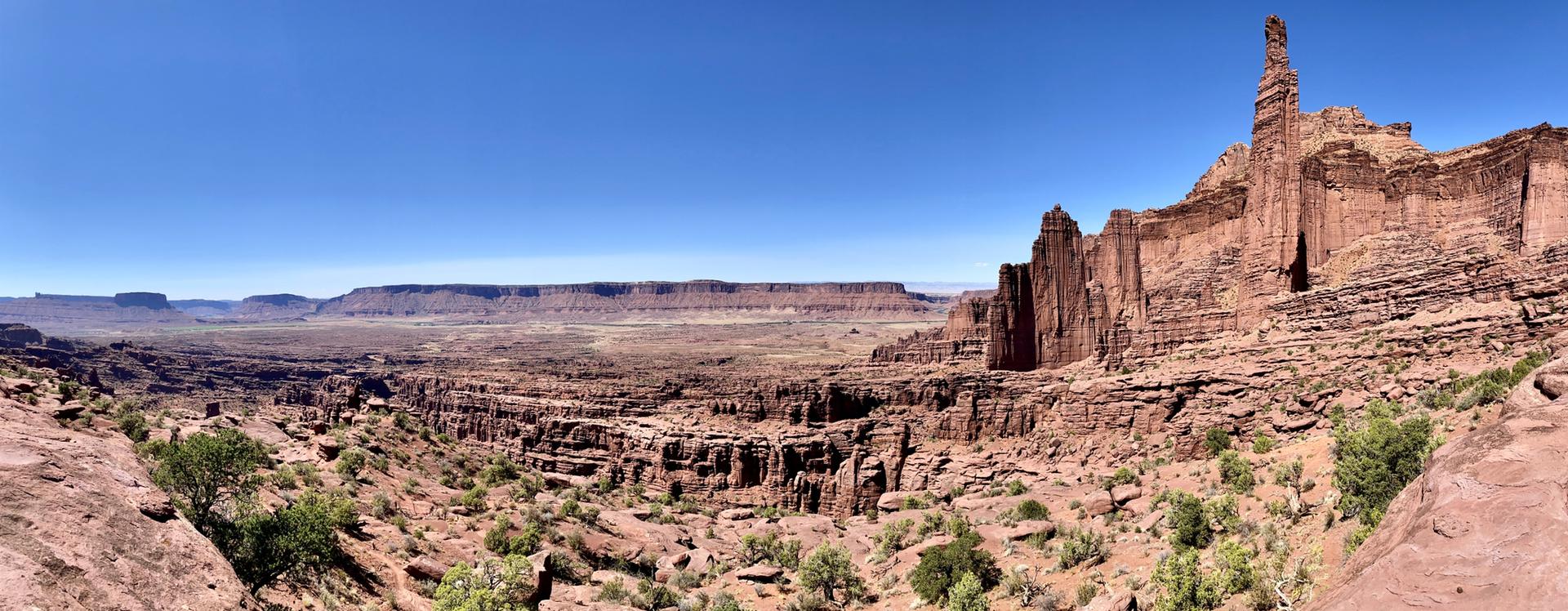 Vast desert landscape with towering red rock formations under a clear blue sky.