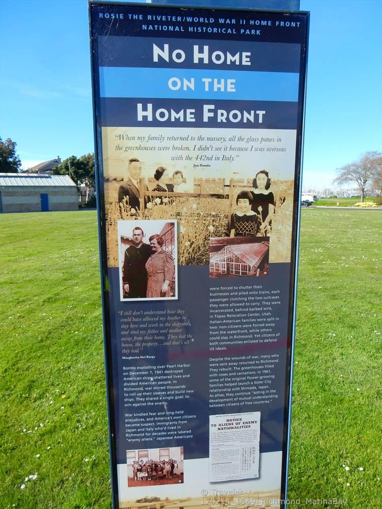 Tall interpretive sign with historical photos and text in a sunny grassy field.