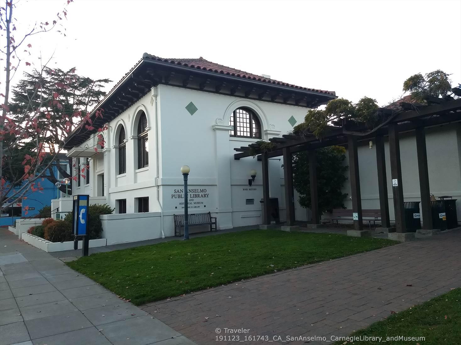 Historic white building with arched windows and a green lawn on an overcast day.