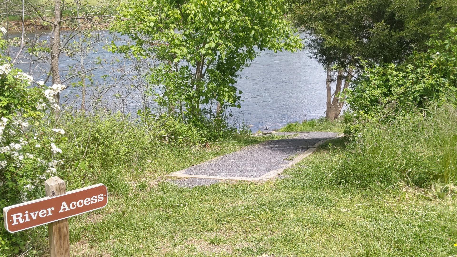 A "River Access" sign next to a paved path leading to water.