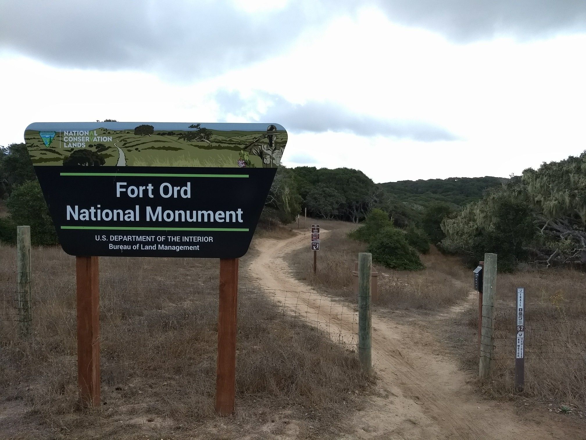 Large sign next to a dirt path leading into a wooded area. - Top of Barloy Canyon Road – Fort Ord ⛰️🚵 MTB trailhead loop from Seaside