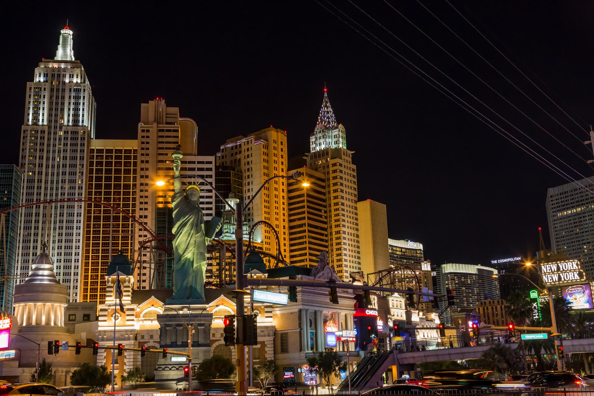Illuminated cityscape at night with a large statue and busy streets.