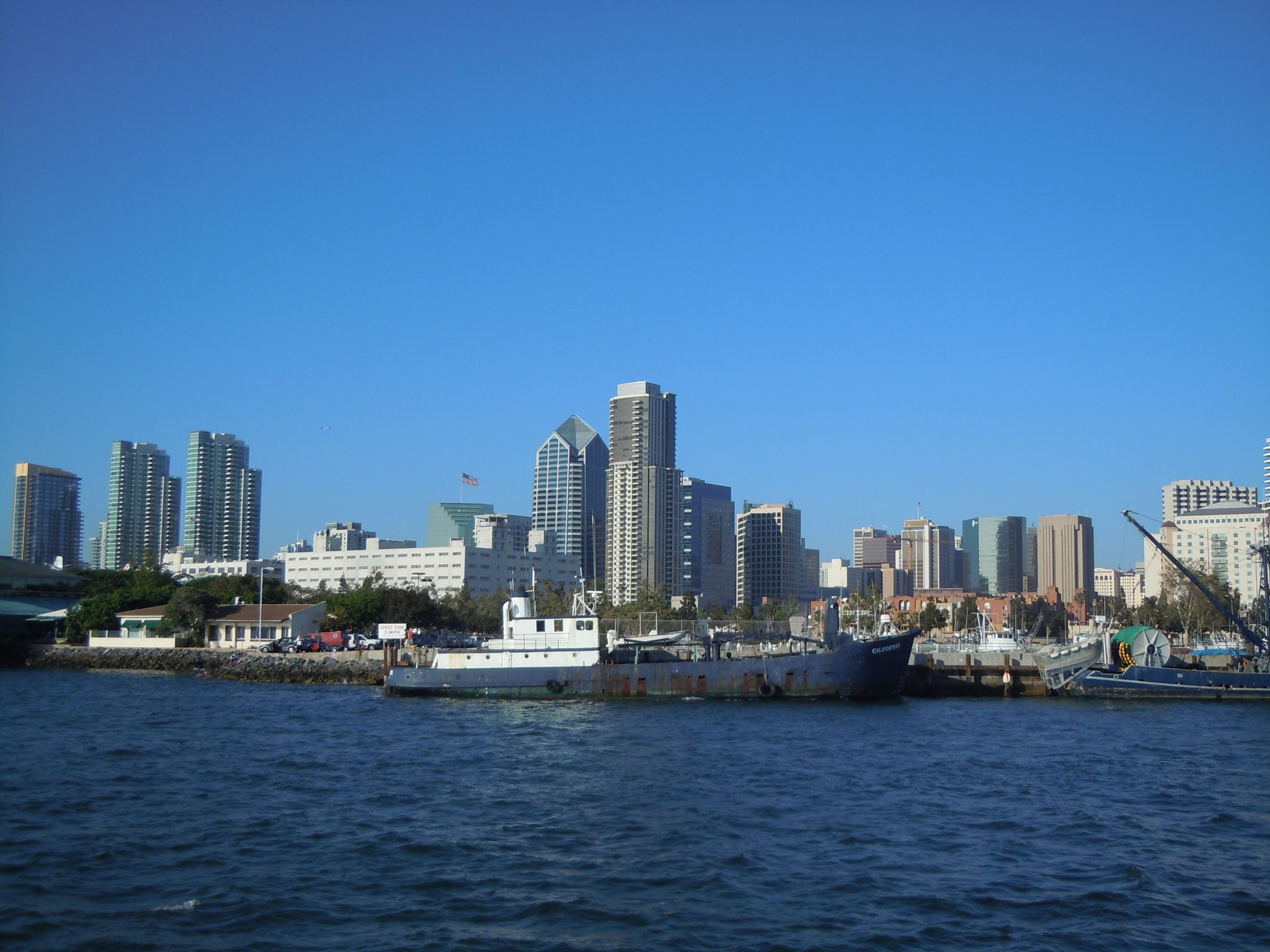 City skyline with boats on calm water under a clear blue sky. - Bayshore Bikeway