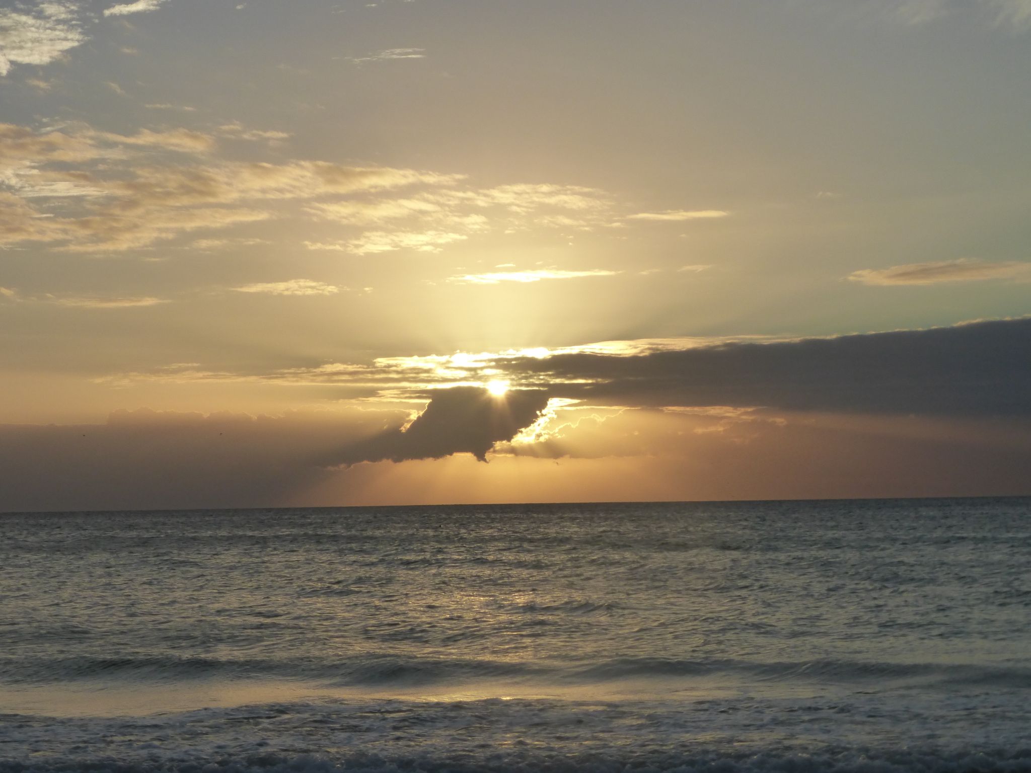 Golden sunset over a calm ocean with sun rays breaking through clouds. - Bradenton Beach loop from Bradenton Beach