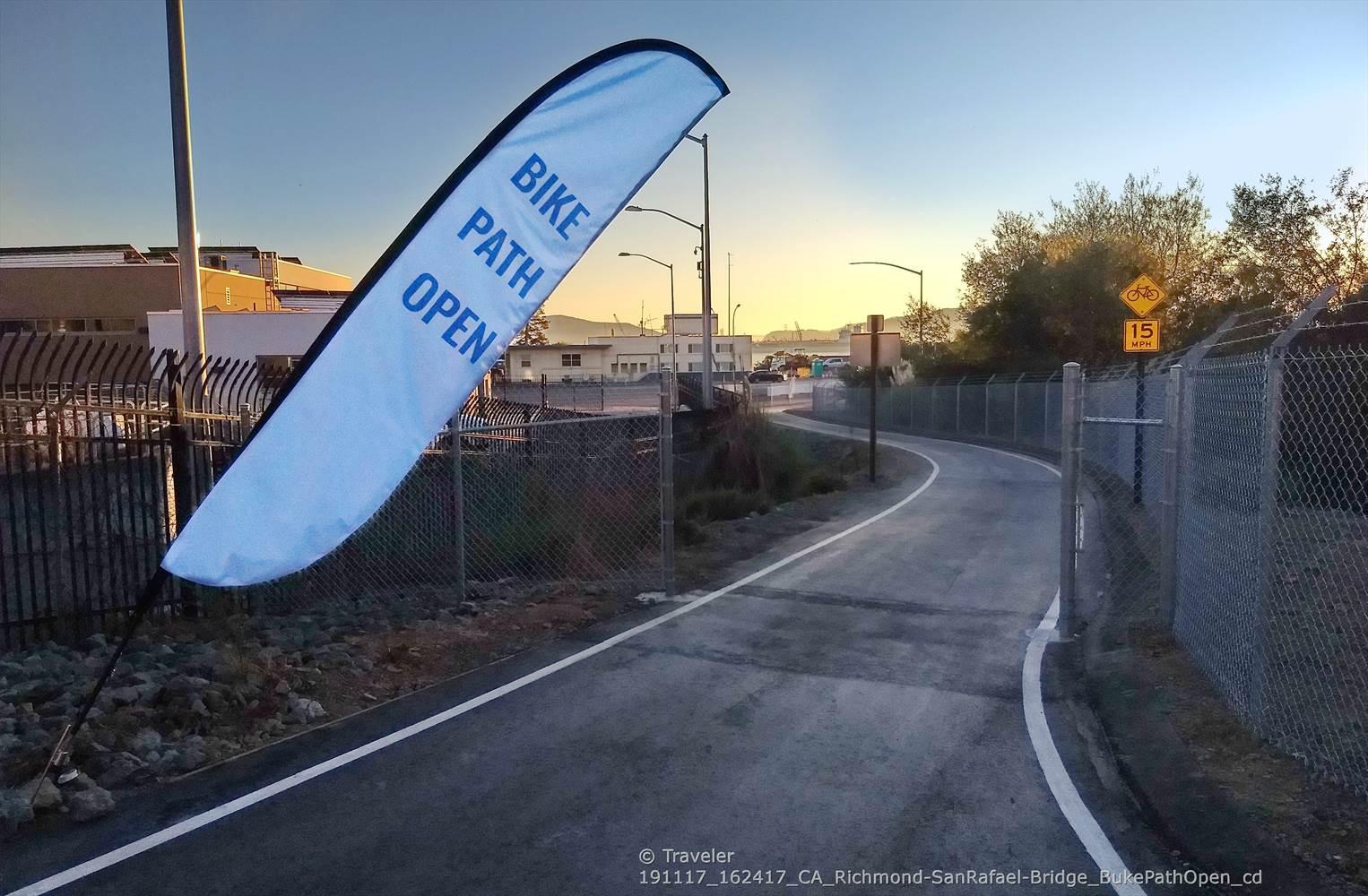 BIKE PATH OPEN flag beside a paved path at sunset.
