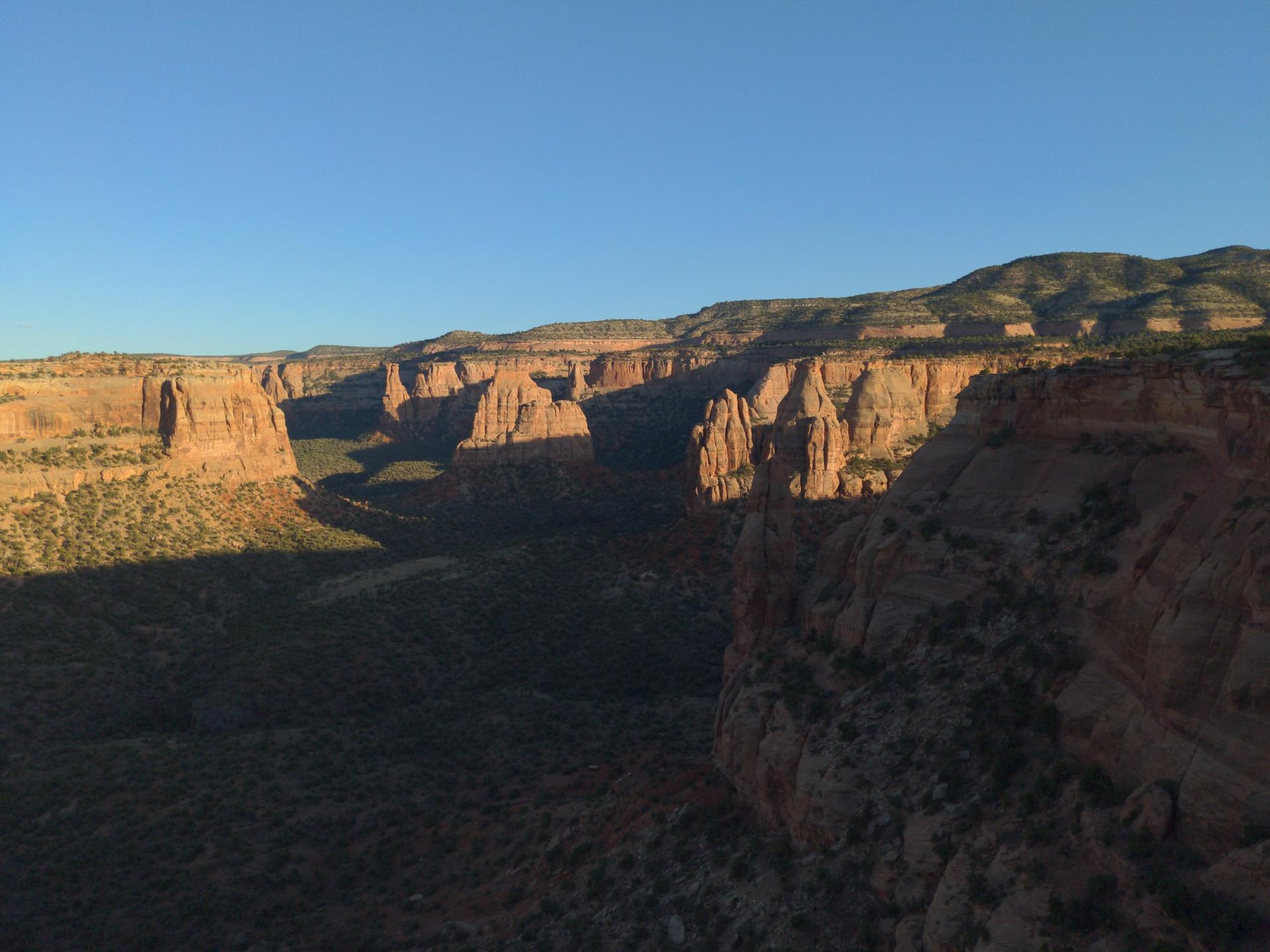 Canyon landscape at sunset, warm light on cliffs, long shadows.