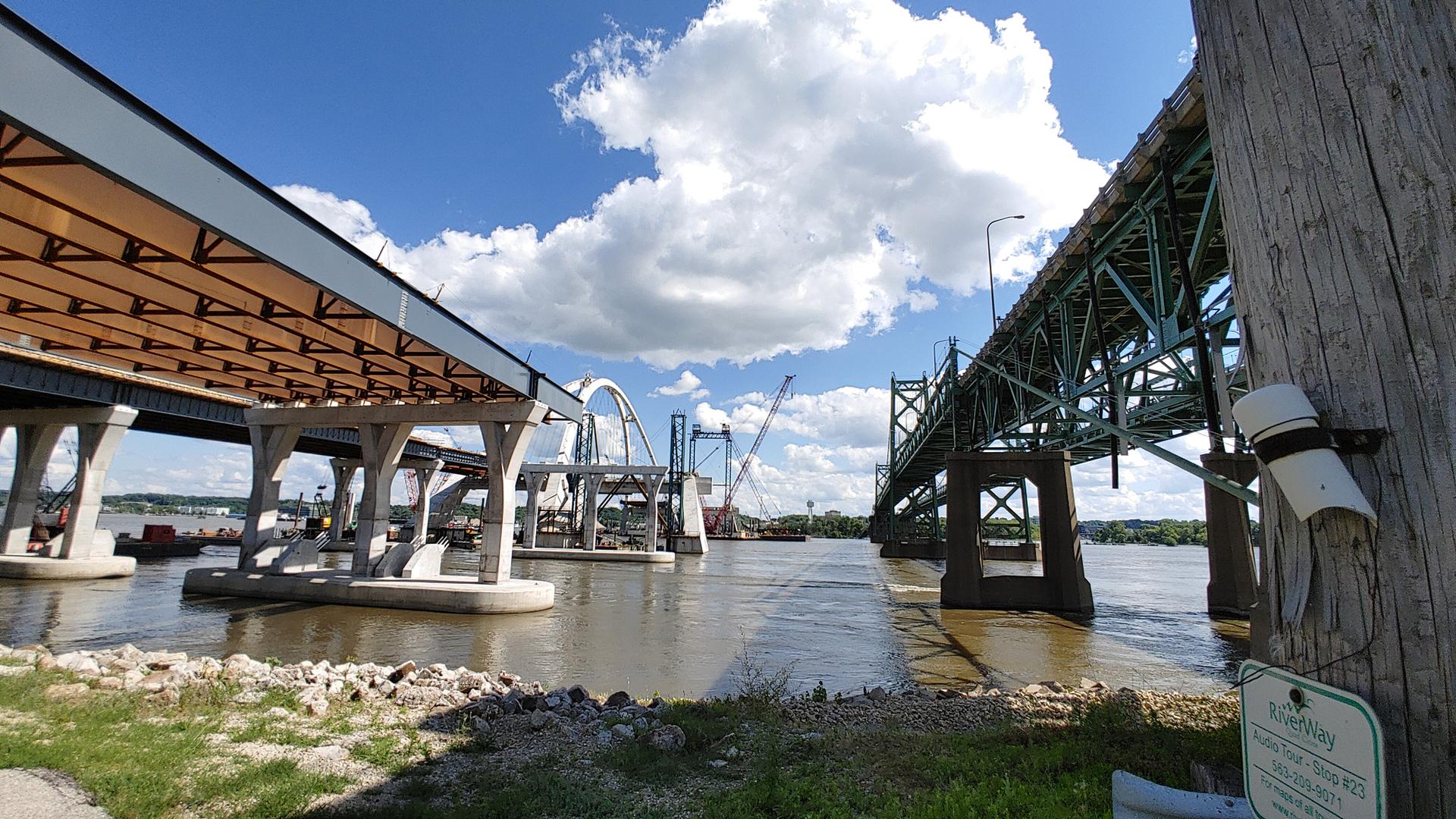 Multiple bridges, old and new, spanning a river on a sunny day.