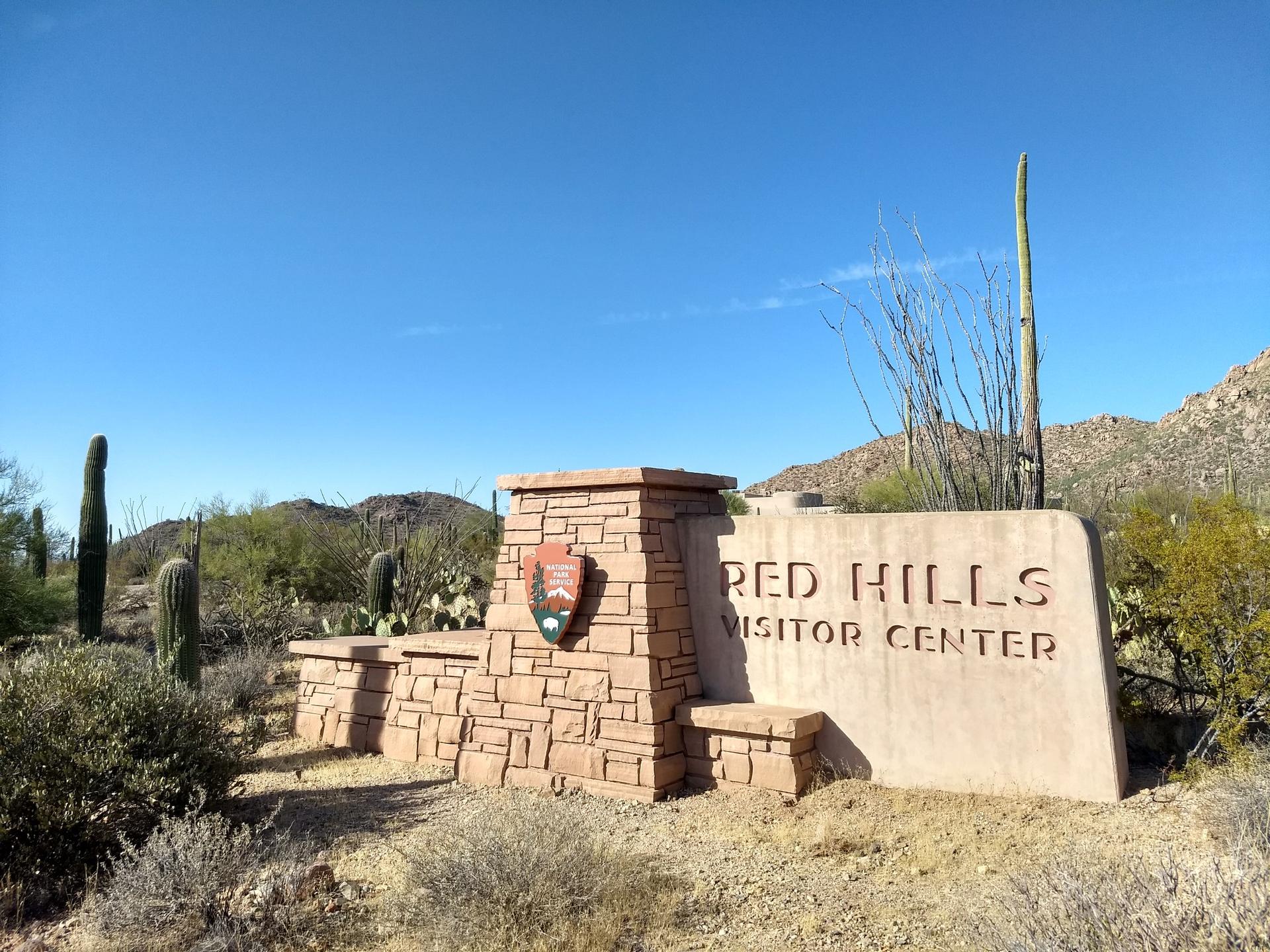 Stone sign for a visitor center in a desert landscape under a clear blue sky.