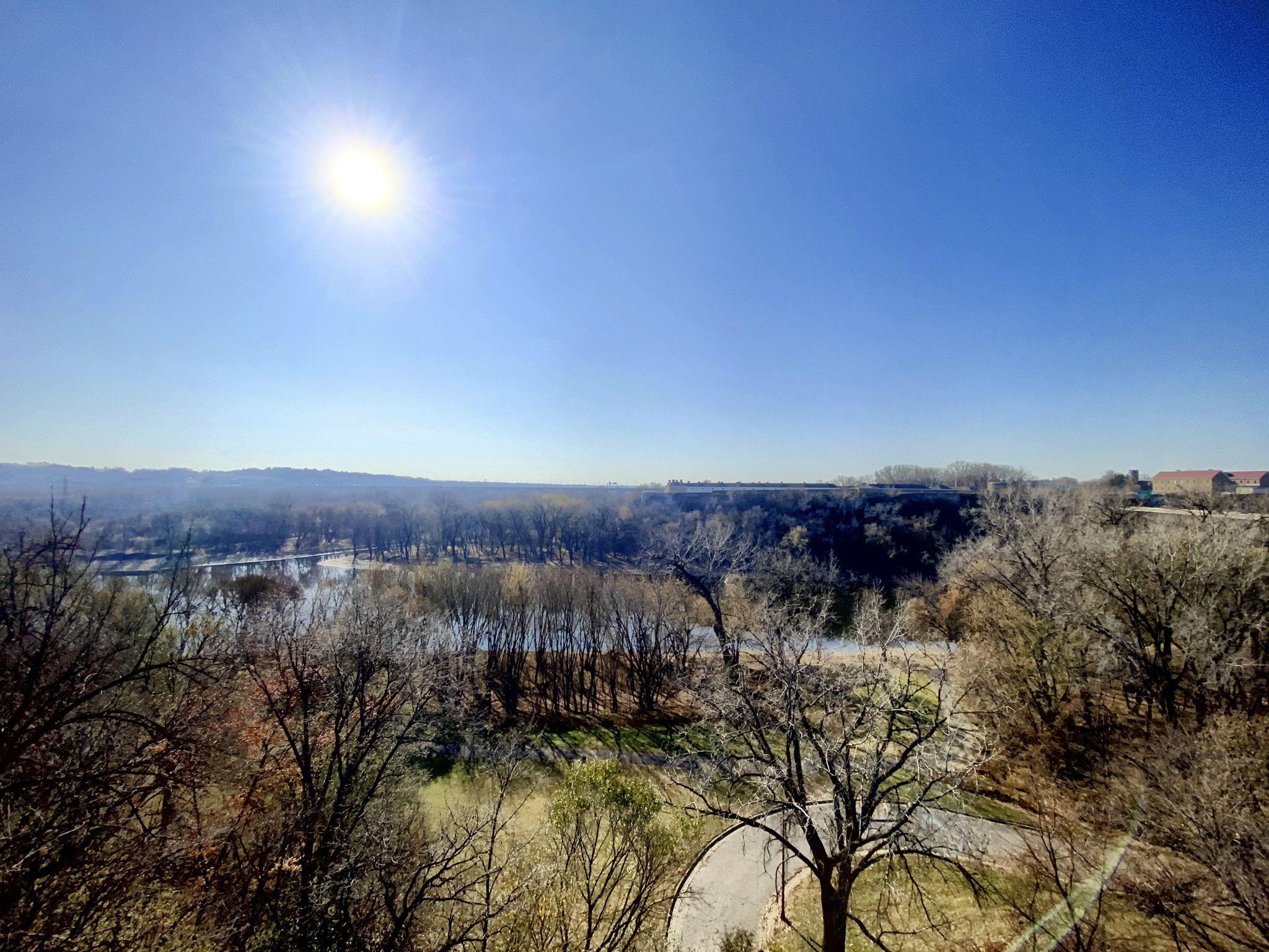 Panoramic view of a wide river valley with bare trees under a bright sunny sky. - Samuel H. Morgan Regional Trail