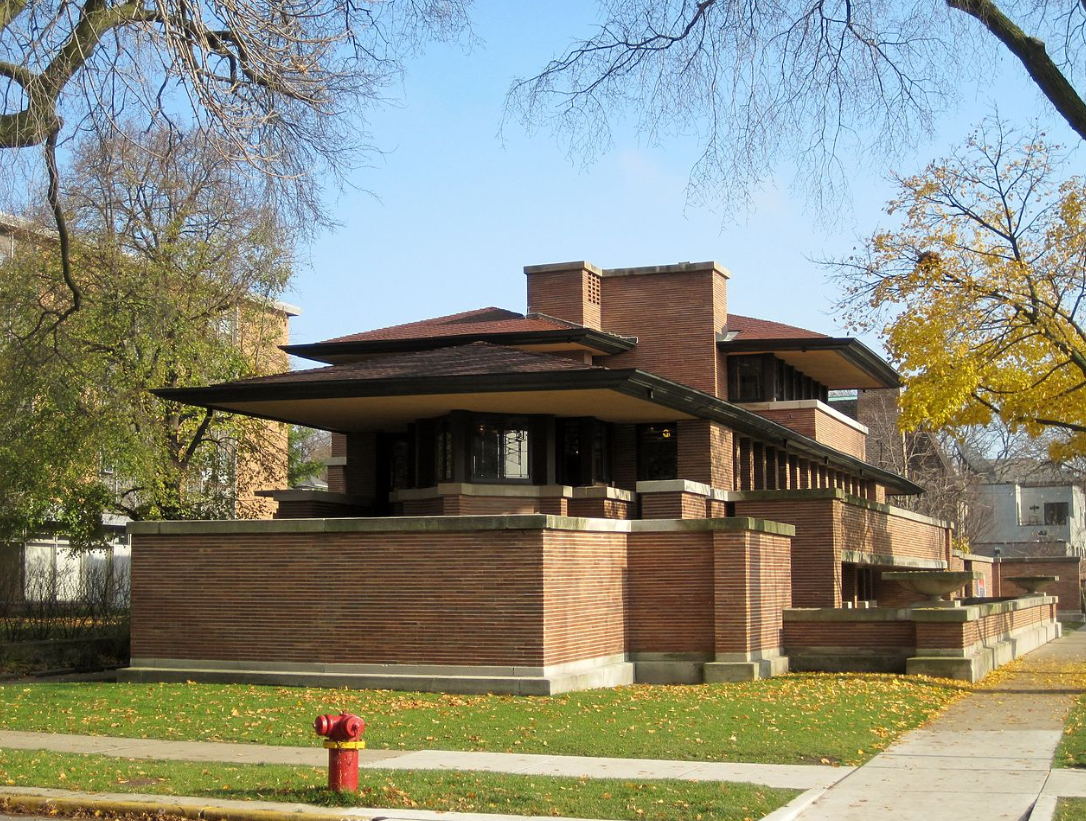 A large brick house with a flat roof on a sunny autumn day.