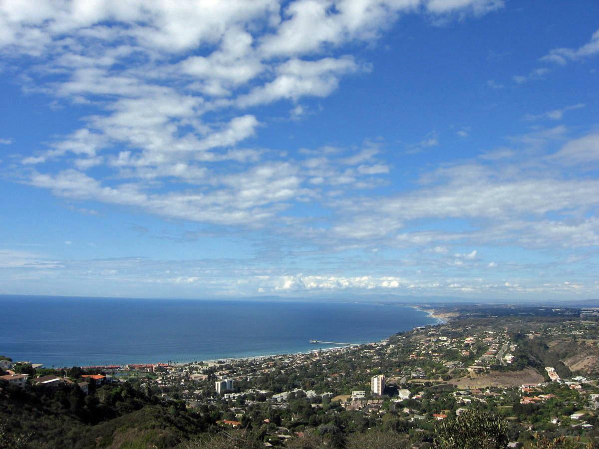 Aerial view of a coastal city beside a vast ocean under a blue sky.
