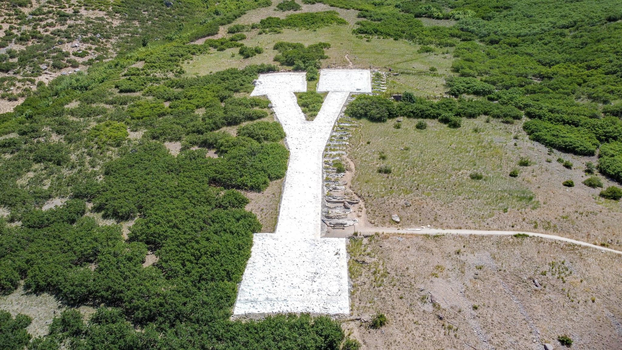 Aerial view of a large white 'Y' symbol on a green hillside.