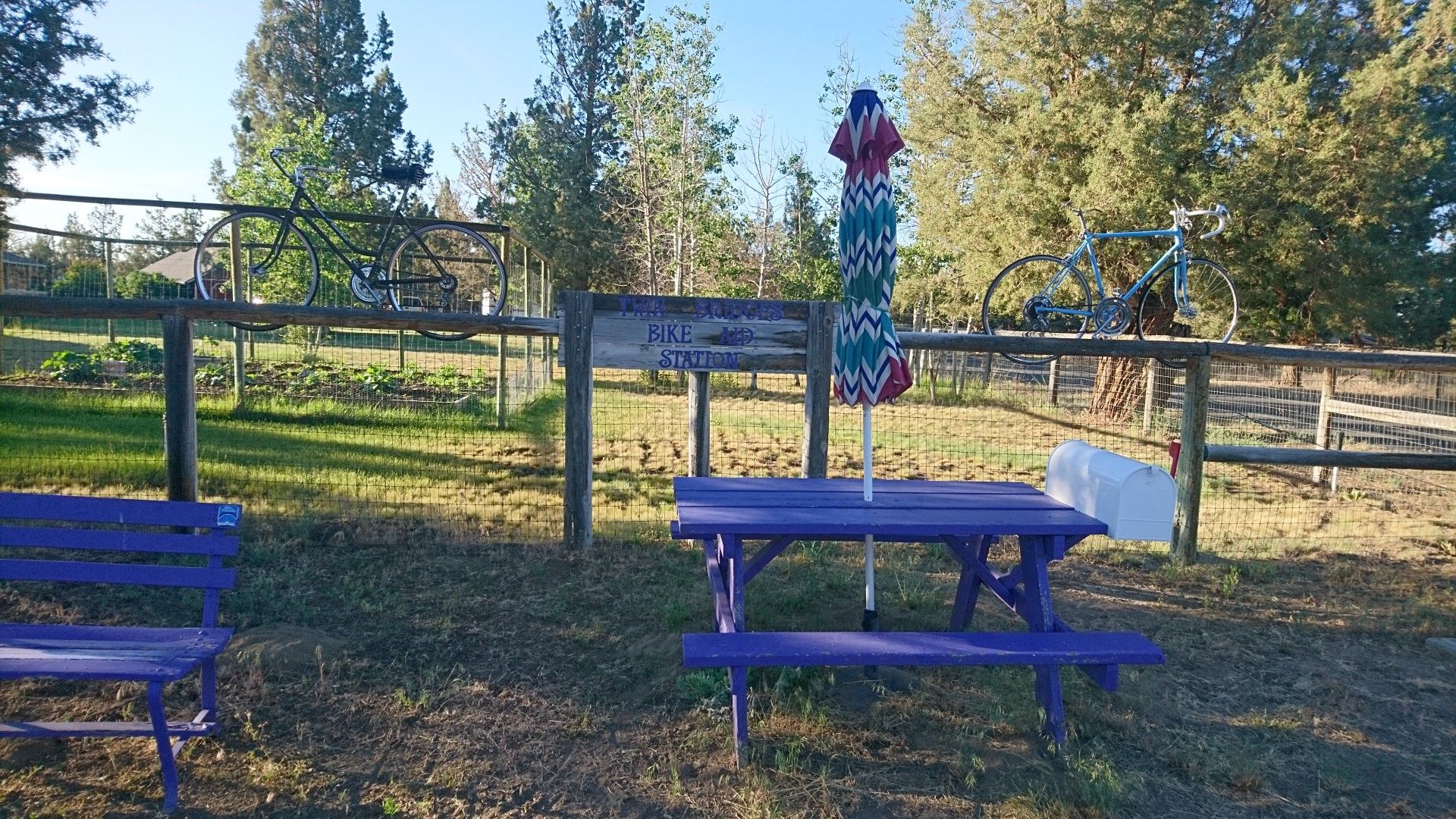 Purple picnic table and bench with bicycles mounted on a wooden fence. - Twin Bridges Scenic Bikeway