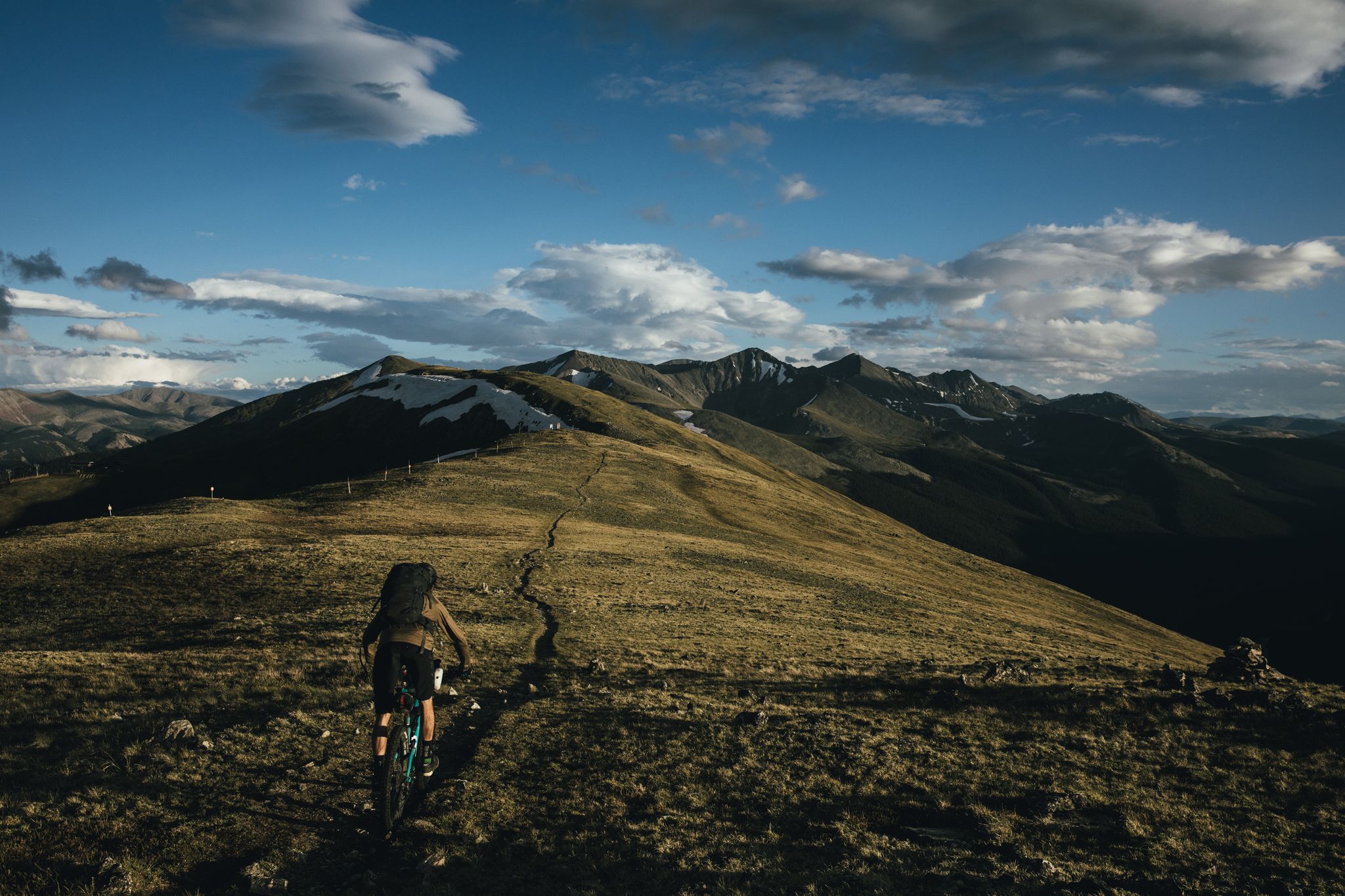 Person pushing a mountain bike up a winding path on a vast mountain. - Colorado Trail: Segment 7