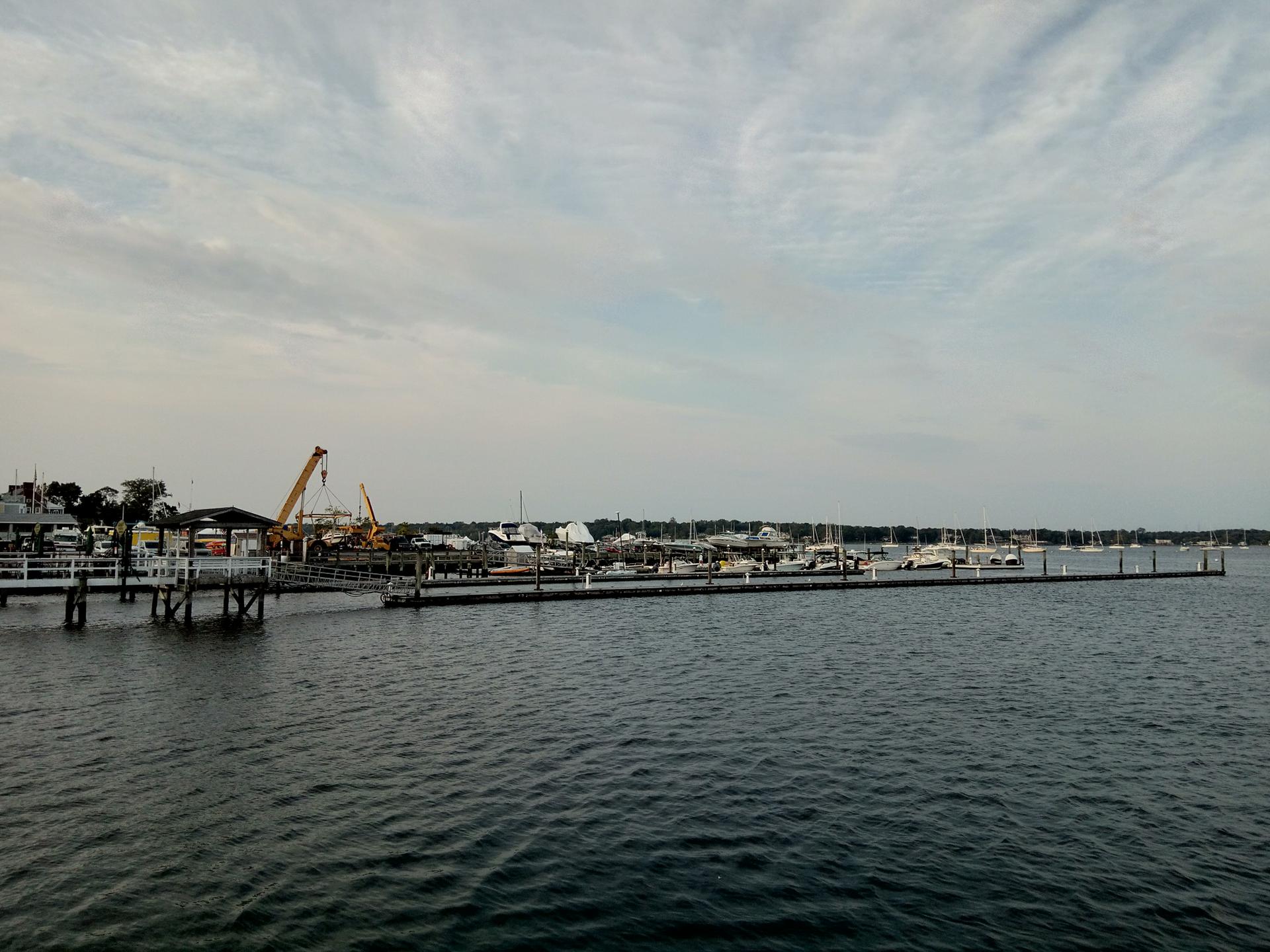 A wide marina with many boats docked along piers under an overcast sky.