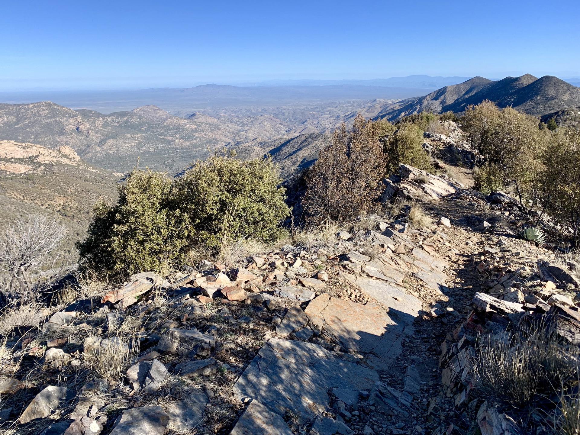 Sunny view of a rocky mountain ridge overlooking a vast valley.