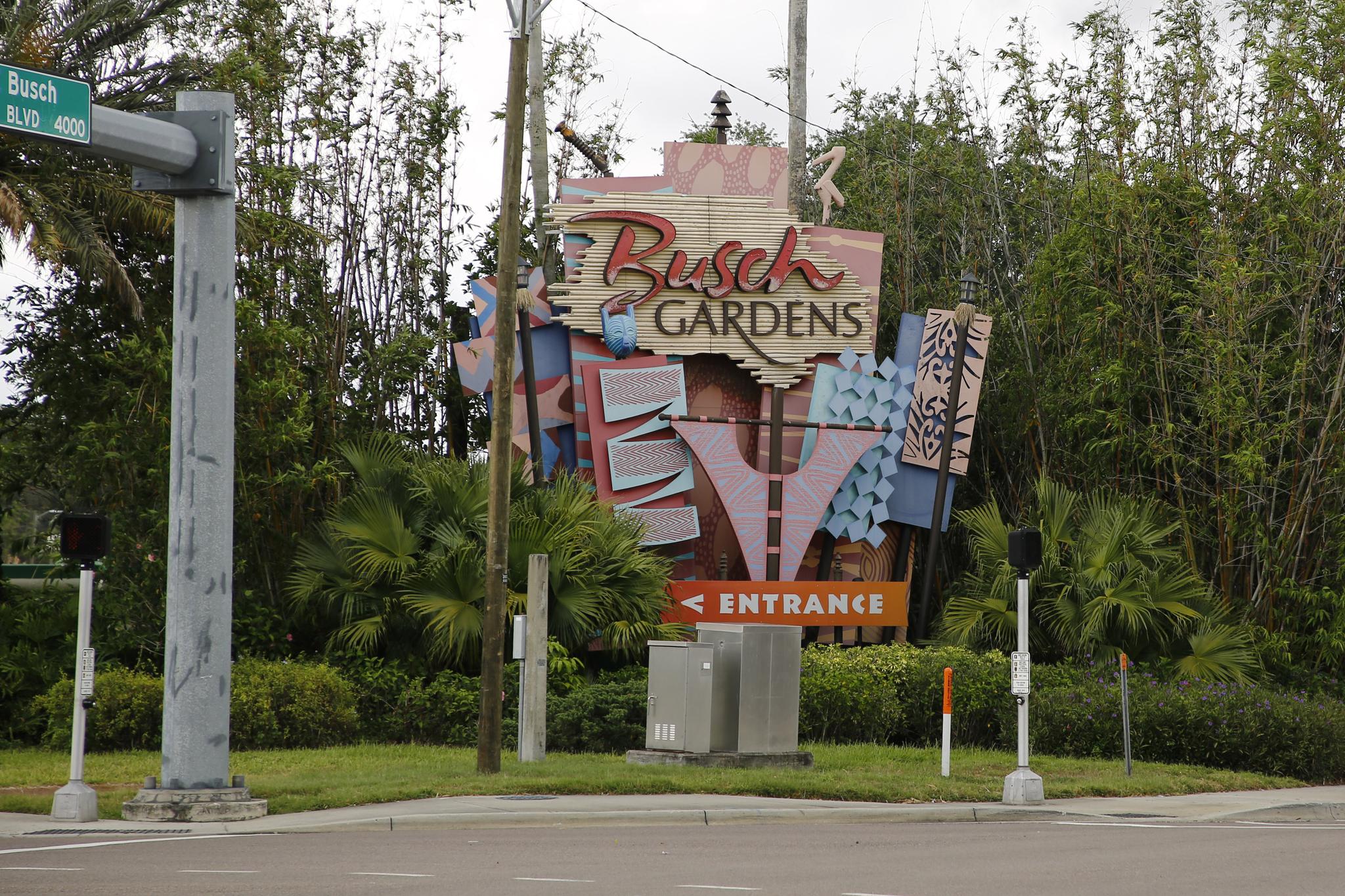 Large, colorful entrance sign for a park, surrounded by lush green foliage.