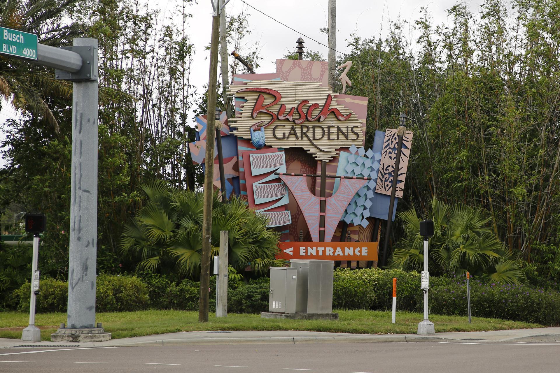 Large, colorful entrance sign for a park, surrounded by lush green foliage.