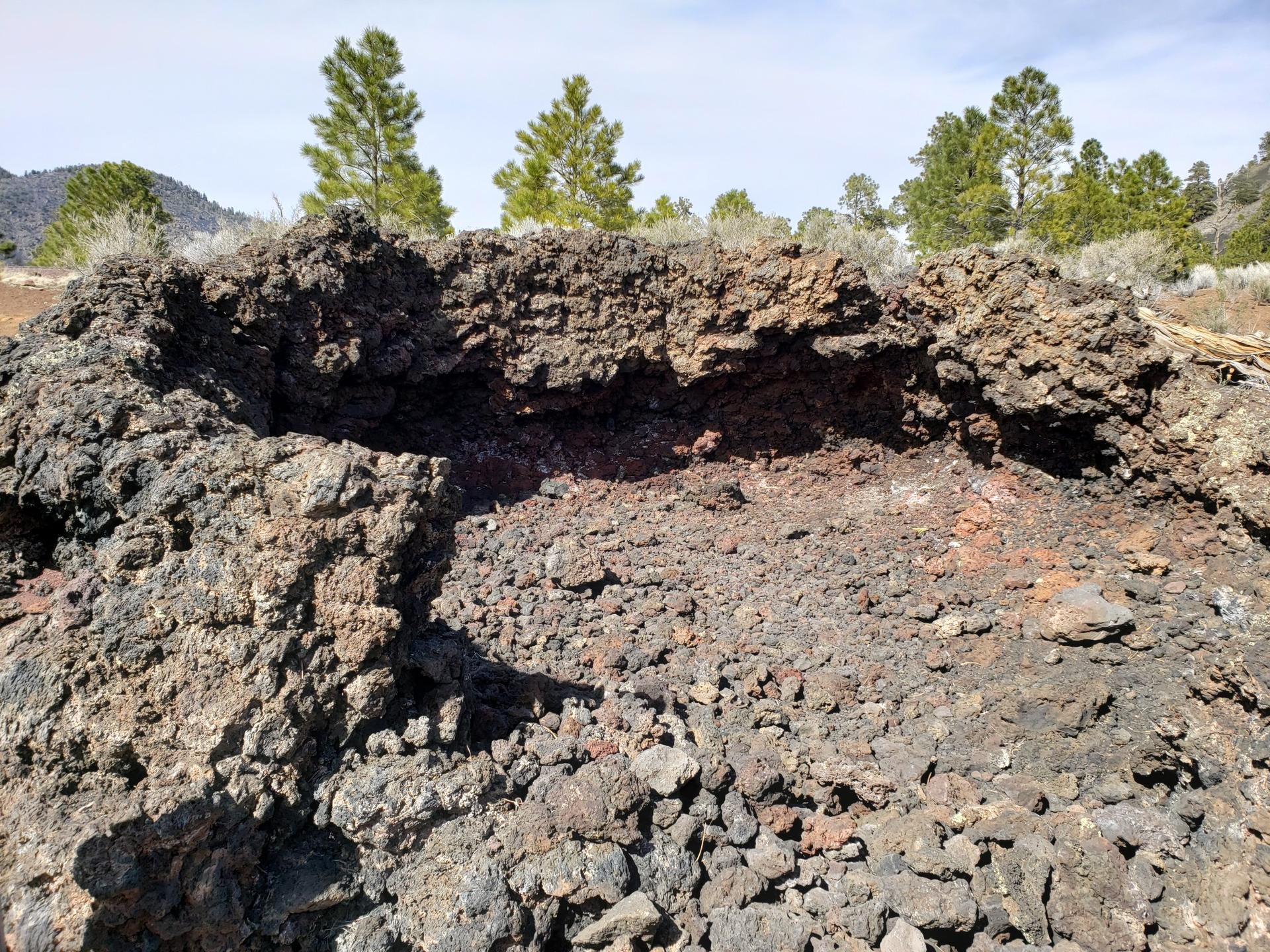 Close-up of dark, rugged volcanic rock with sparse vegetation under bright light.