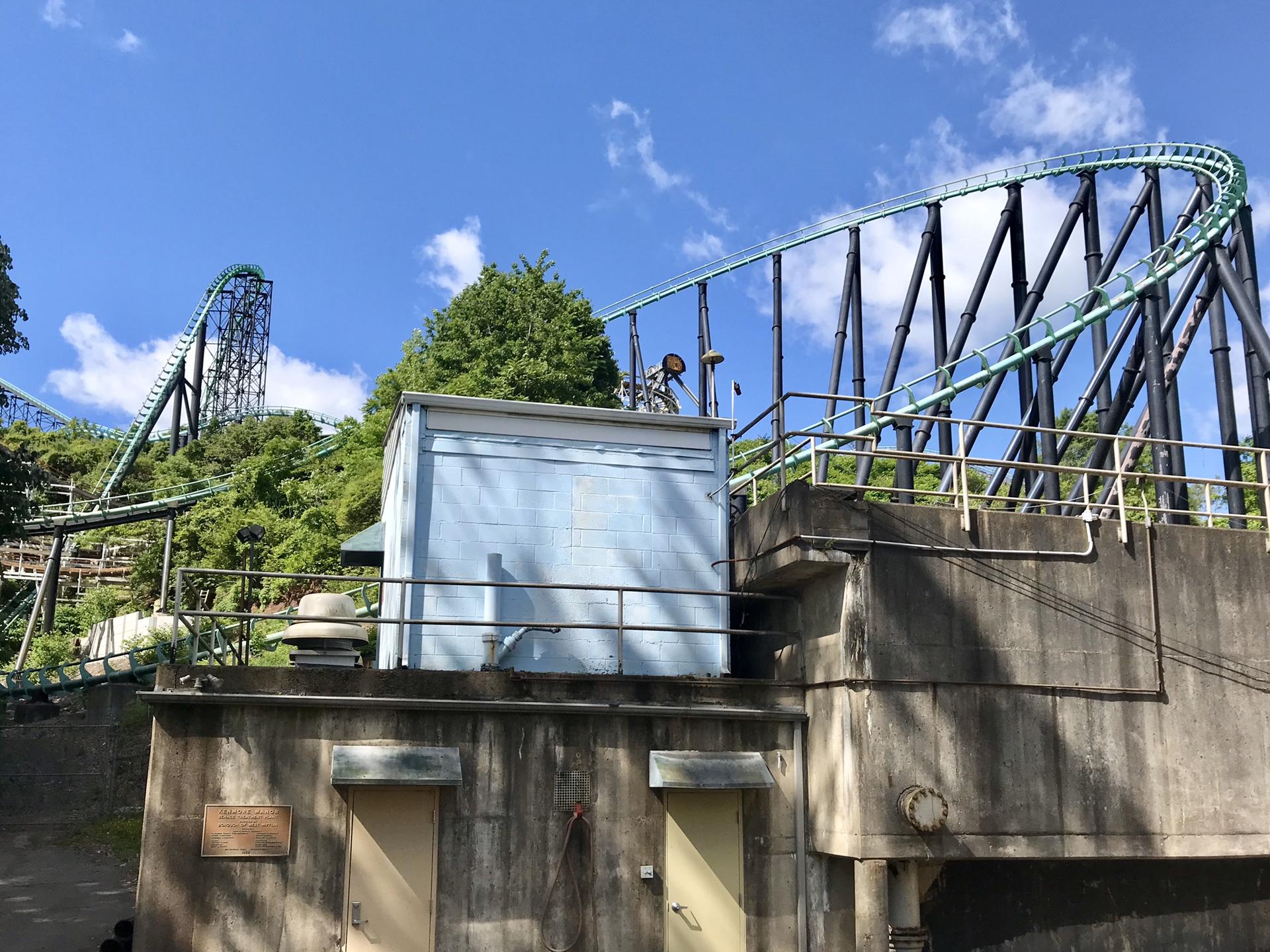 A rollercoaster track winds over a hill, with a blue sky above.