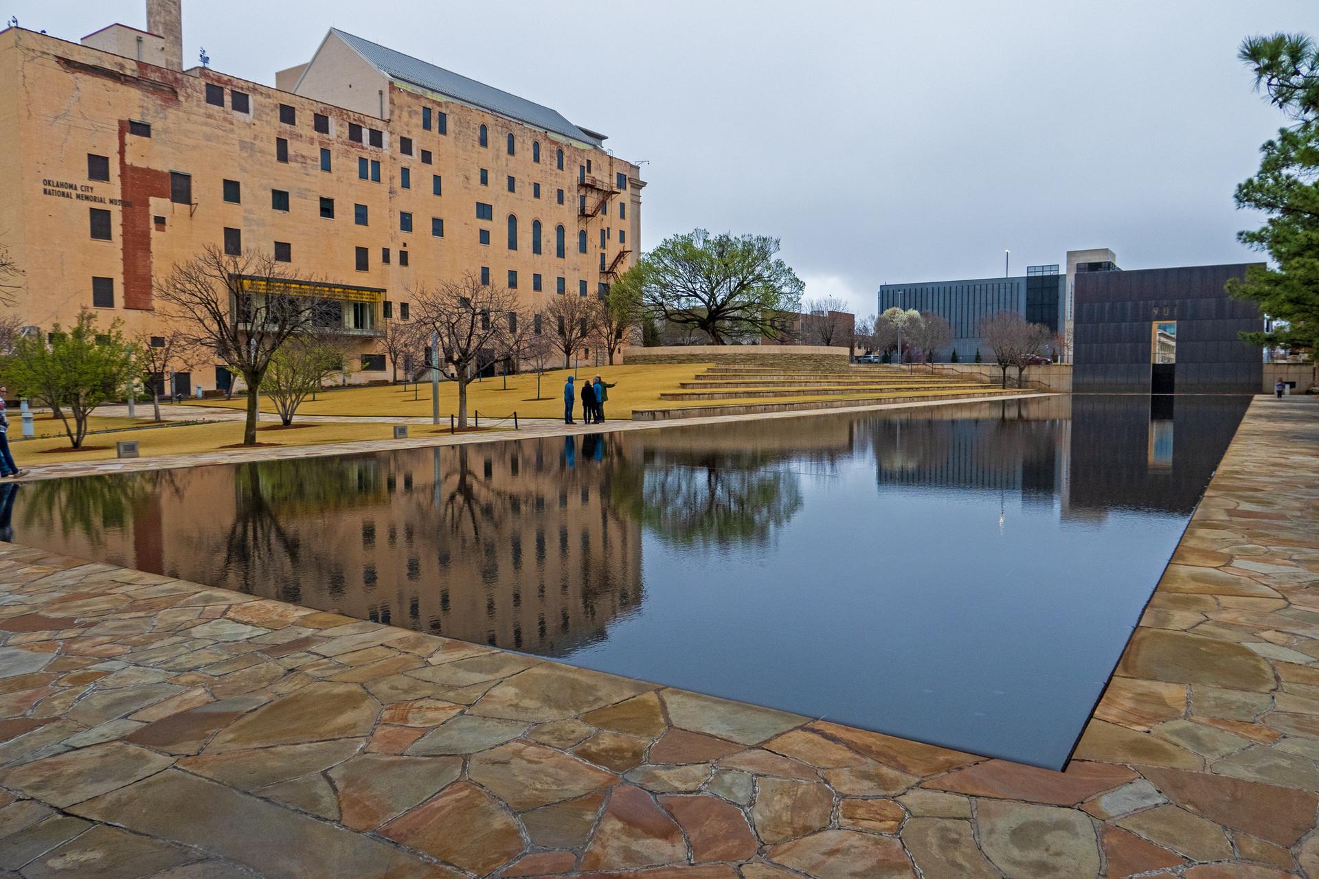 Reflecting pool in front of a large brick building with people.