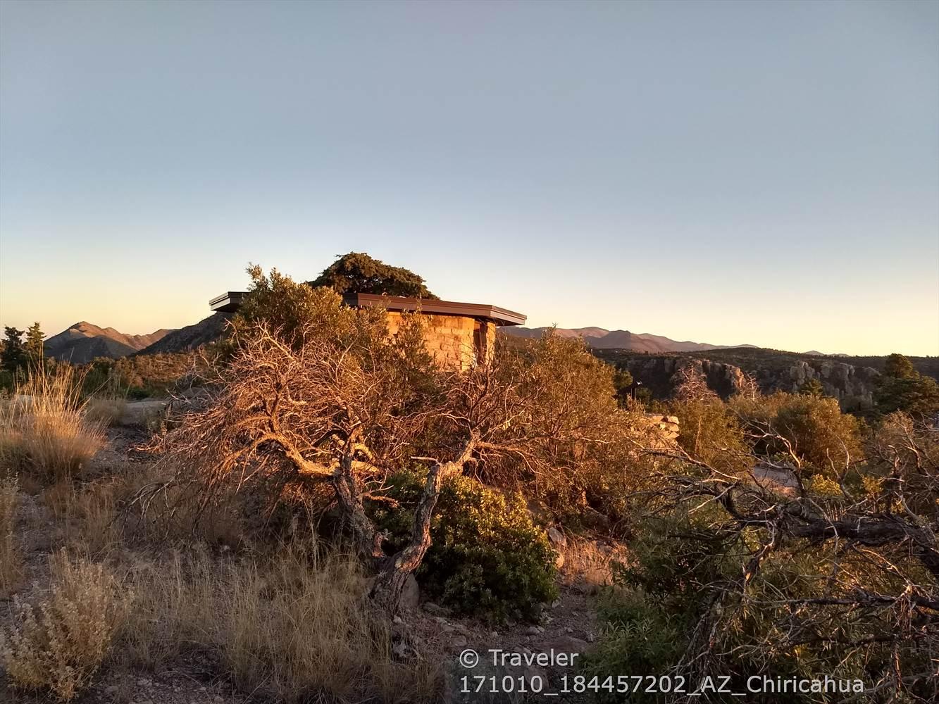 Stone building on a hill, surrounded by dry trees, bathed in golden light.