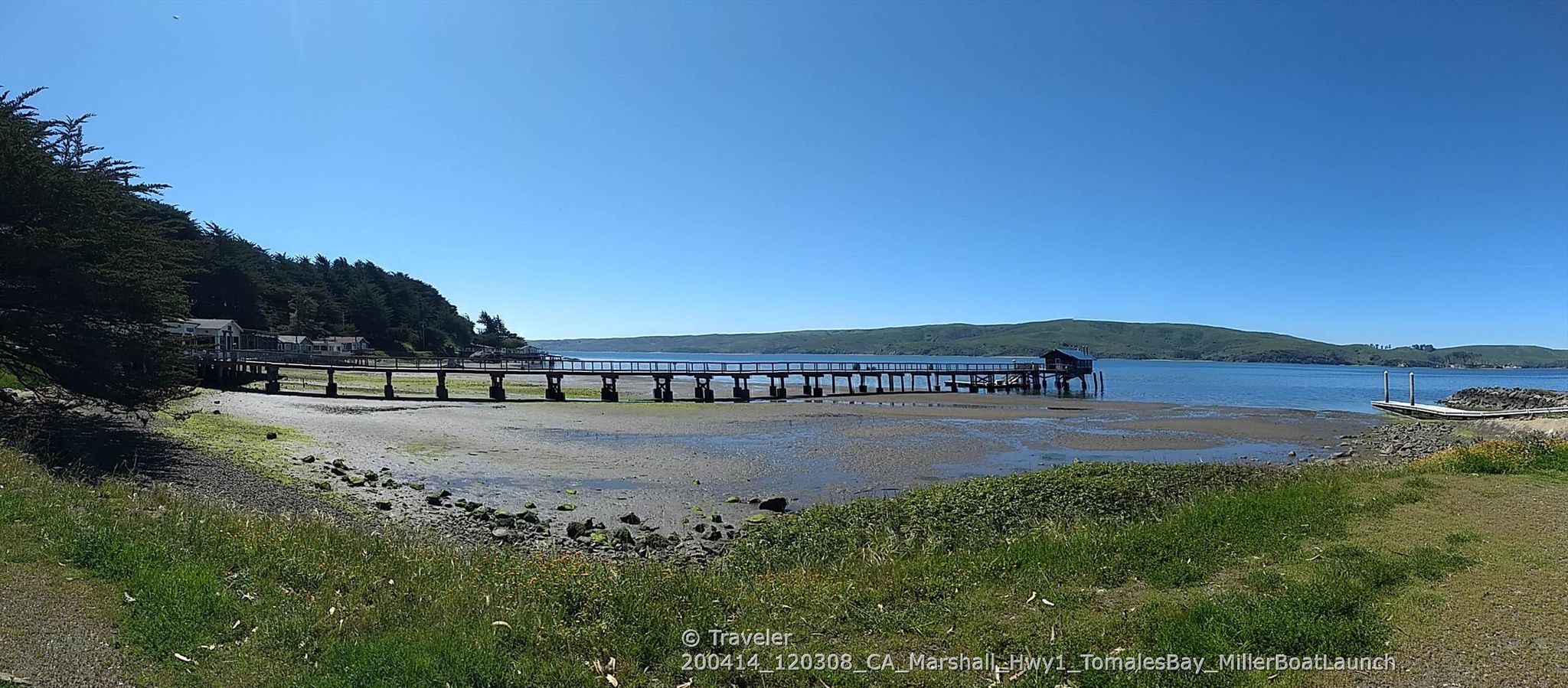 Panoramic view of a long pier extending into a calm bay at low tide. - Marin Coastal and Pacific Coast Bike Route