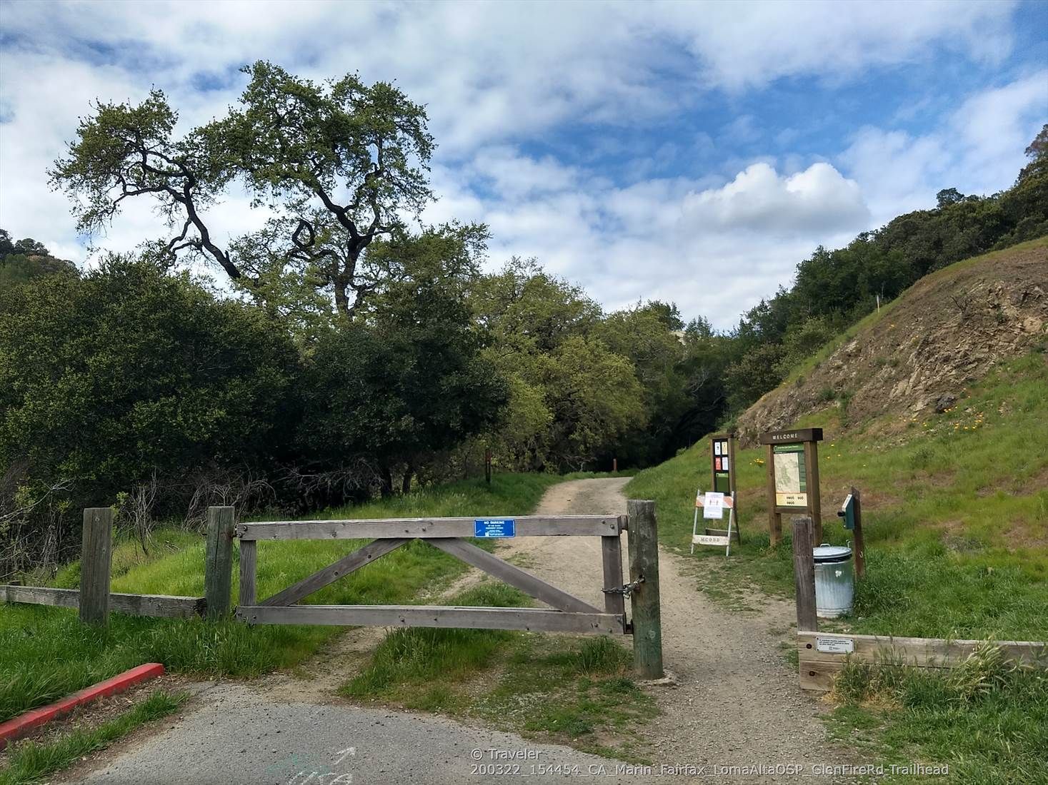 A wooden gate marks a dirt trail entrance with information signs and green hills. - Glen Fire Rd Trailhead 🌳 loop from Piper Lane Presere