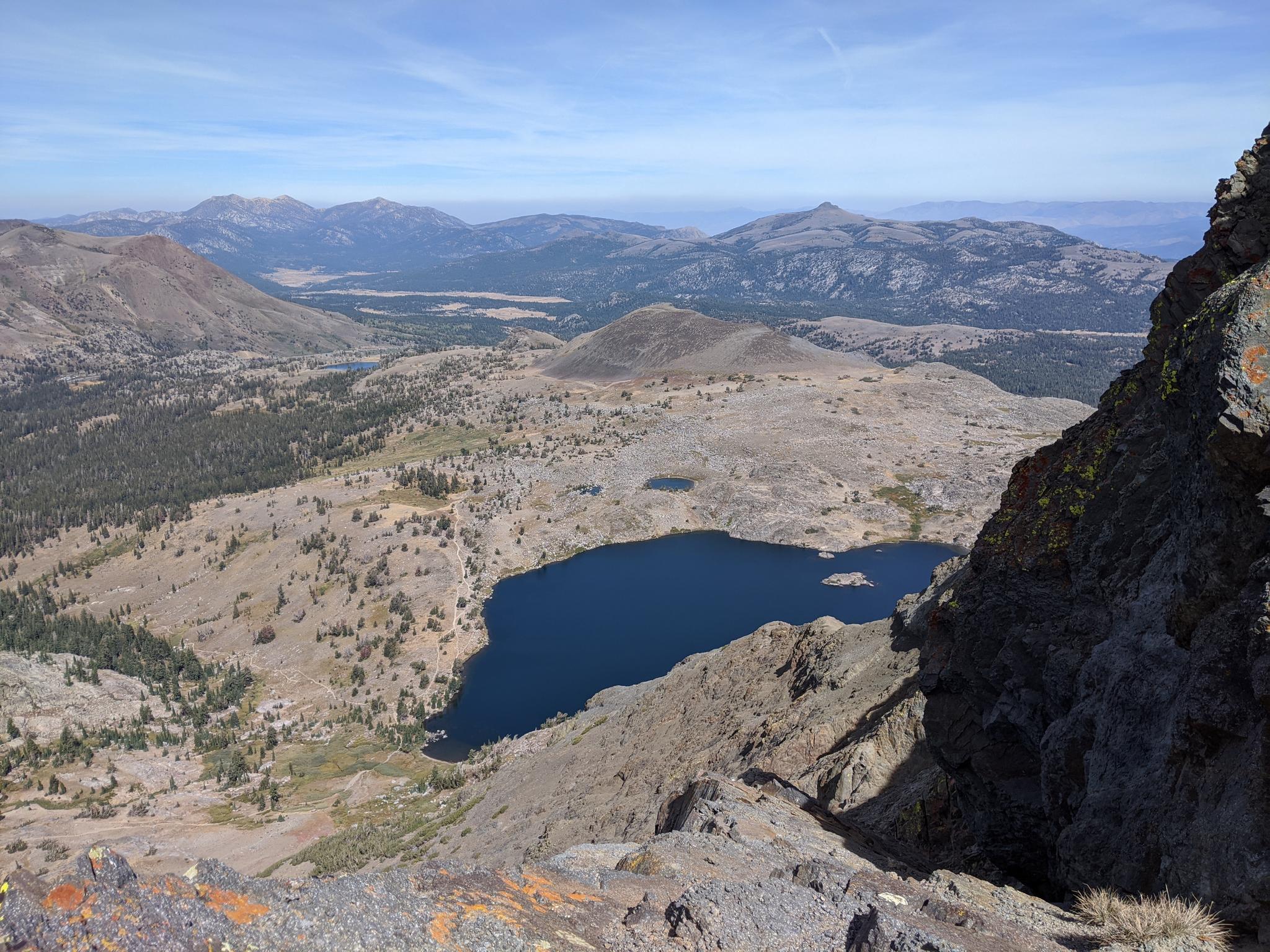 Panoramic view of a deep blue lake nestled in a vast mountain landscape.