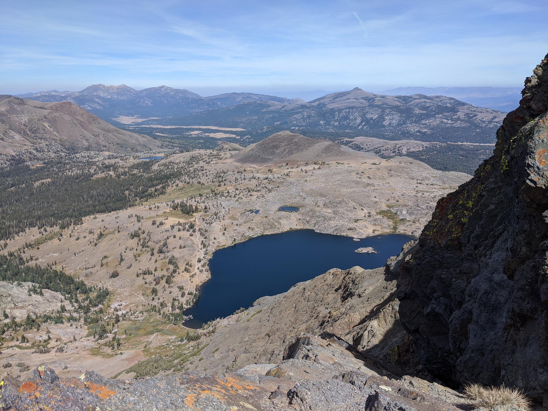 Panoramic view of a deep blue lake nestled in a vast mountain landscape.